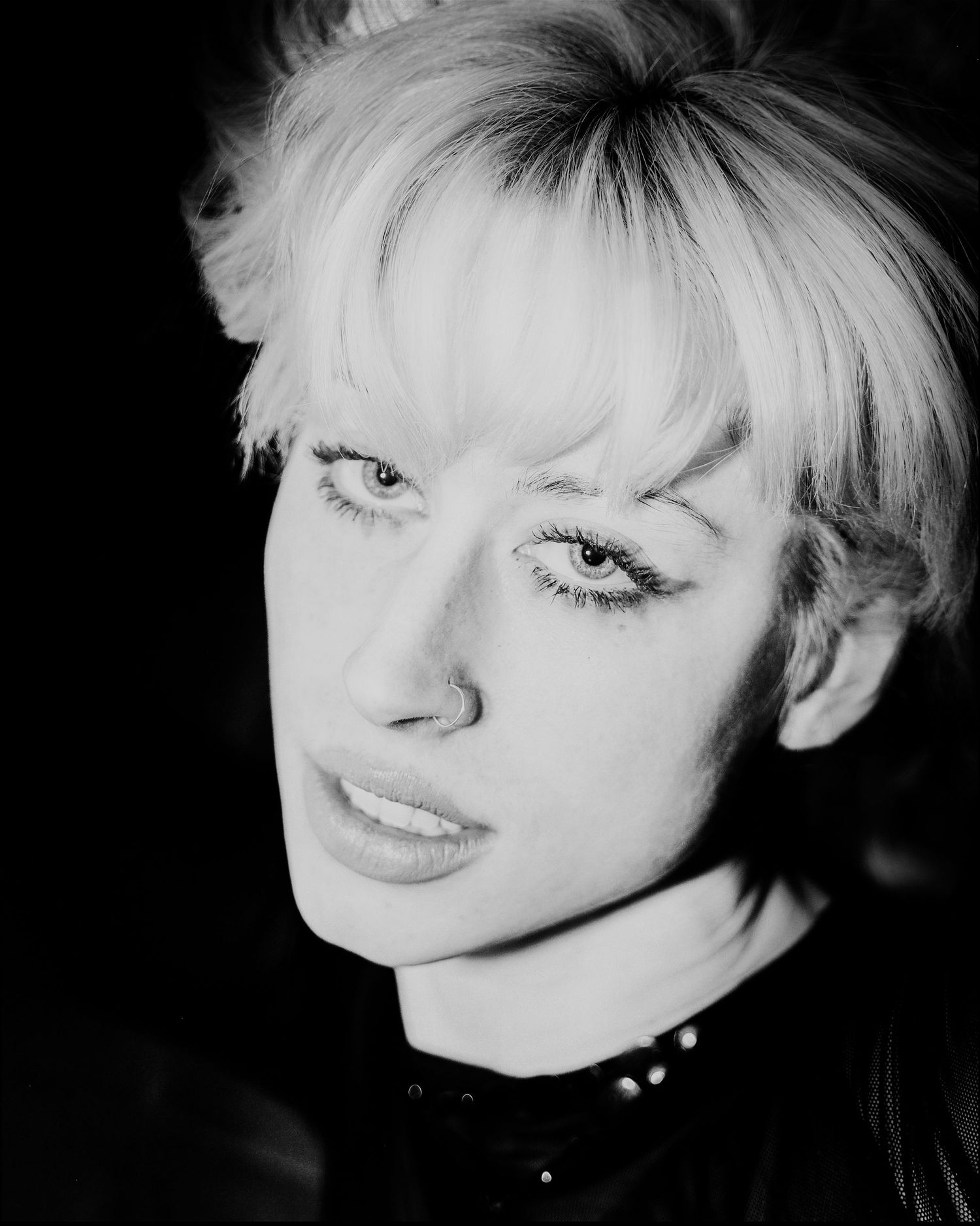 Black and white close-up portrait of blonde woman with intense gaze.