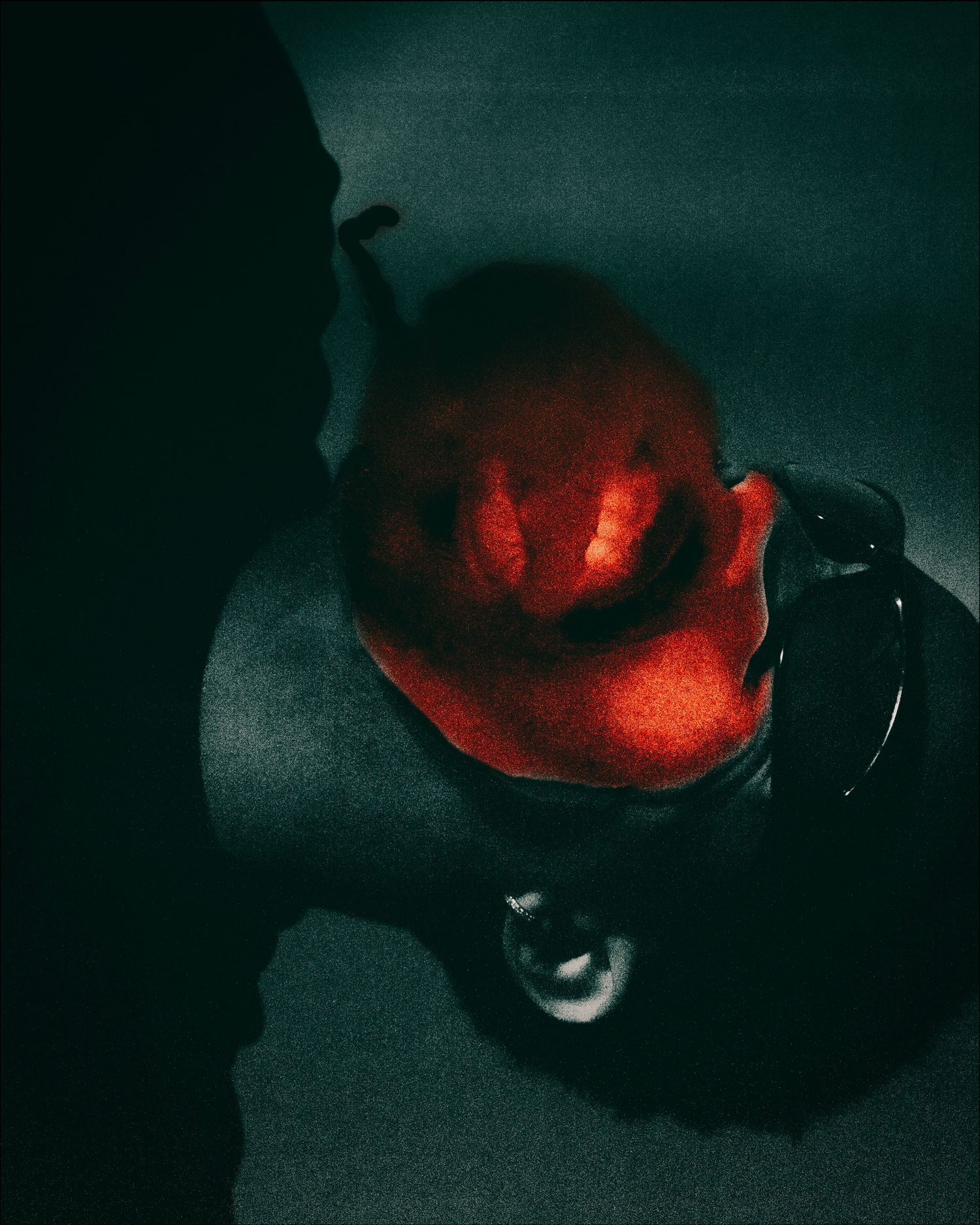 Upside-down face with red glowing mouth reflected on dark surface.