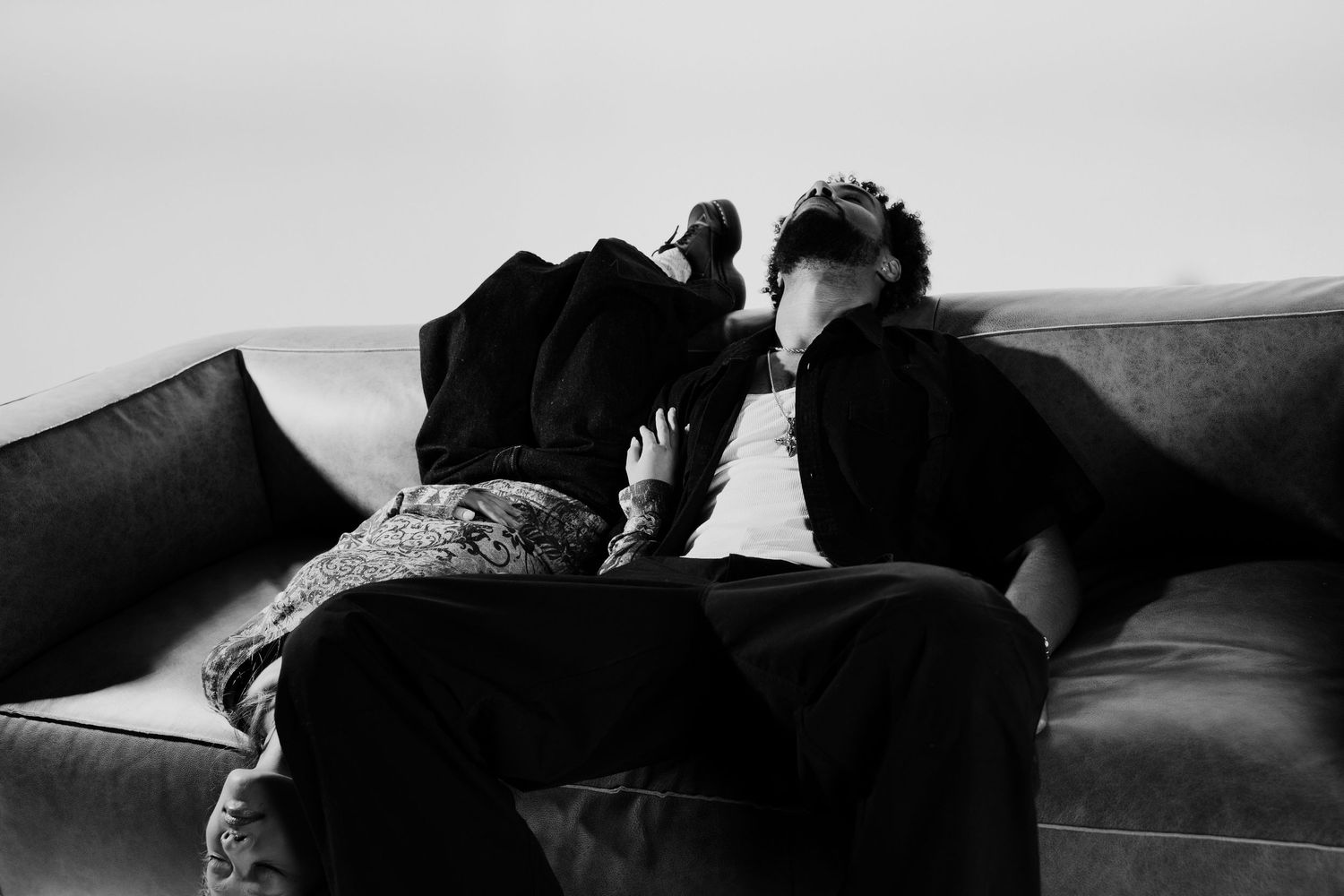 Black and white photo of two people leaning close together on a grey sofa.