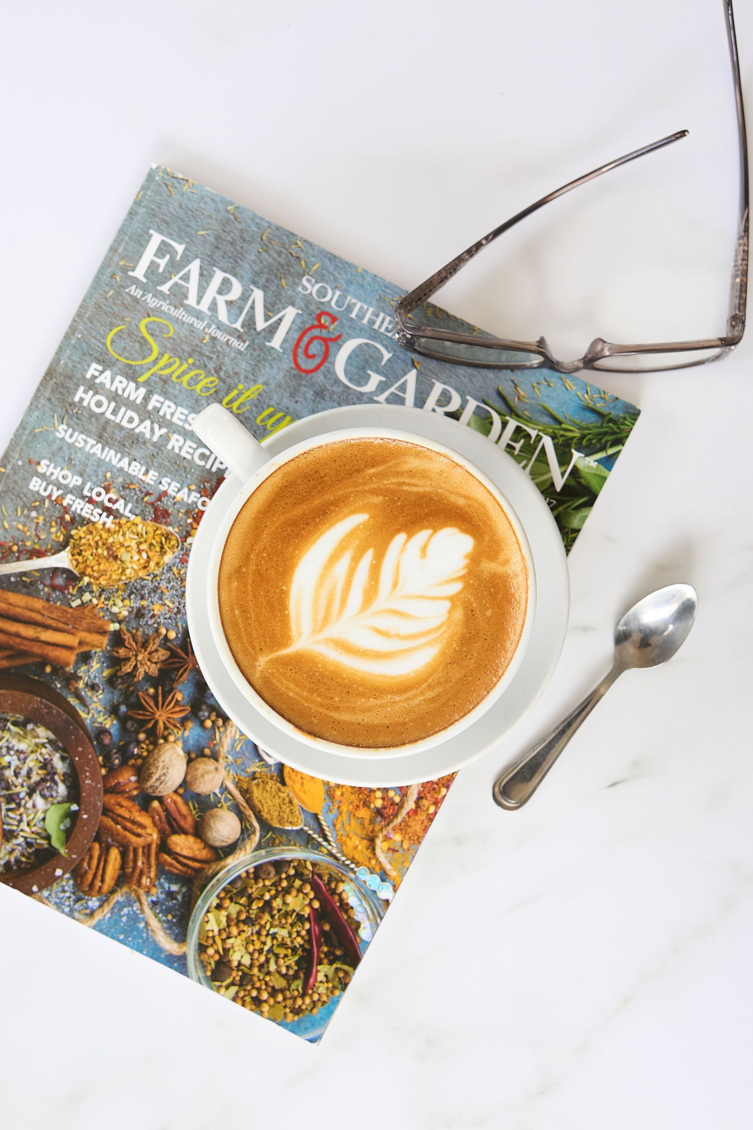 Crema coffee and Southern Farm & Garden magazine arranged on a rustic tabletop, photographed in soft, natural light.
