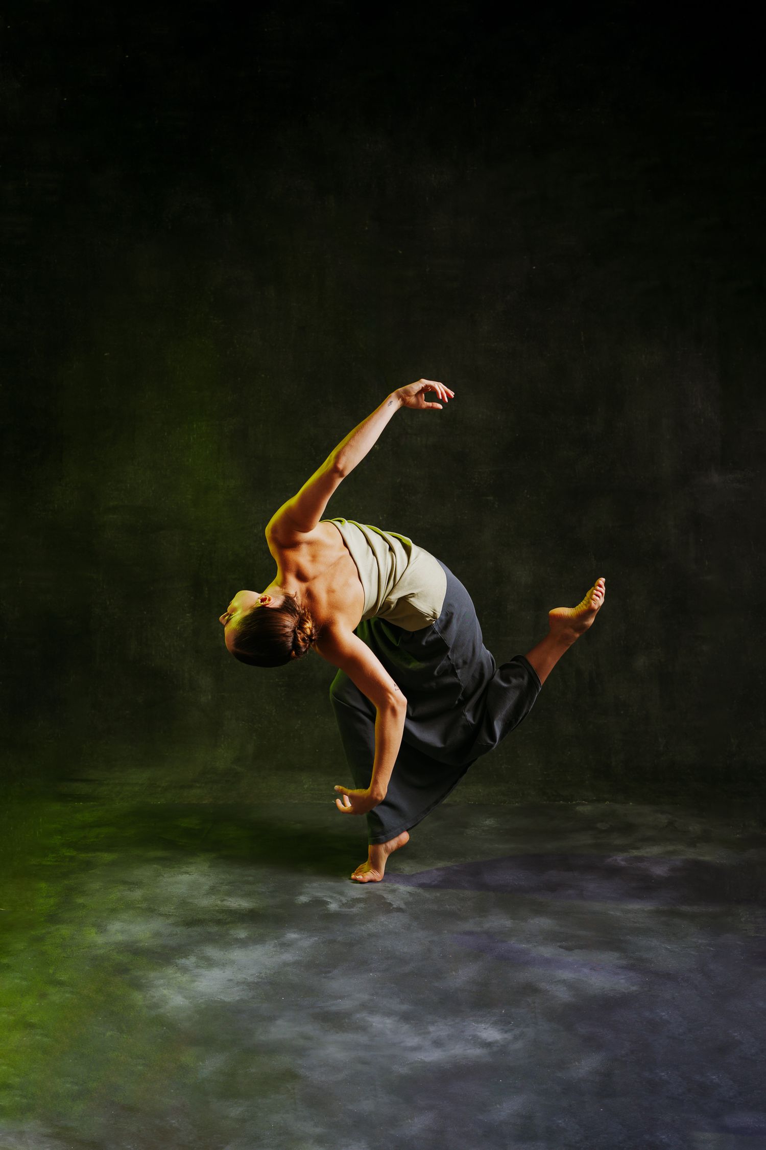 Dancer performs a dynamic breakdance sequence with fluid movements against a dark background with green lighting.