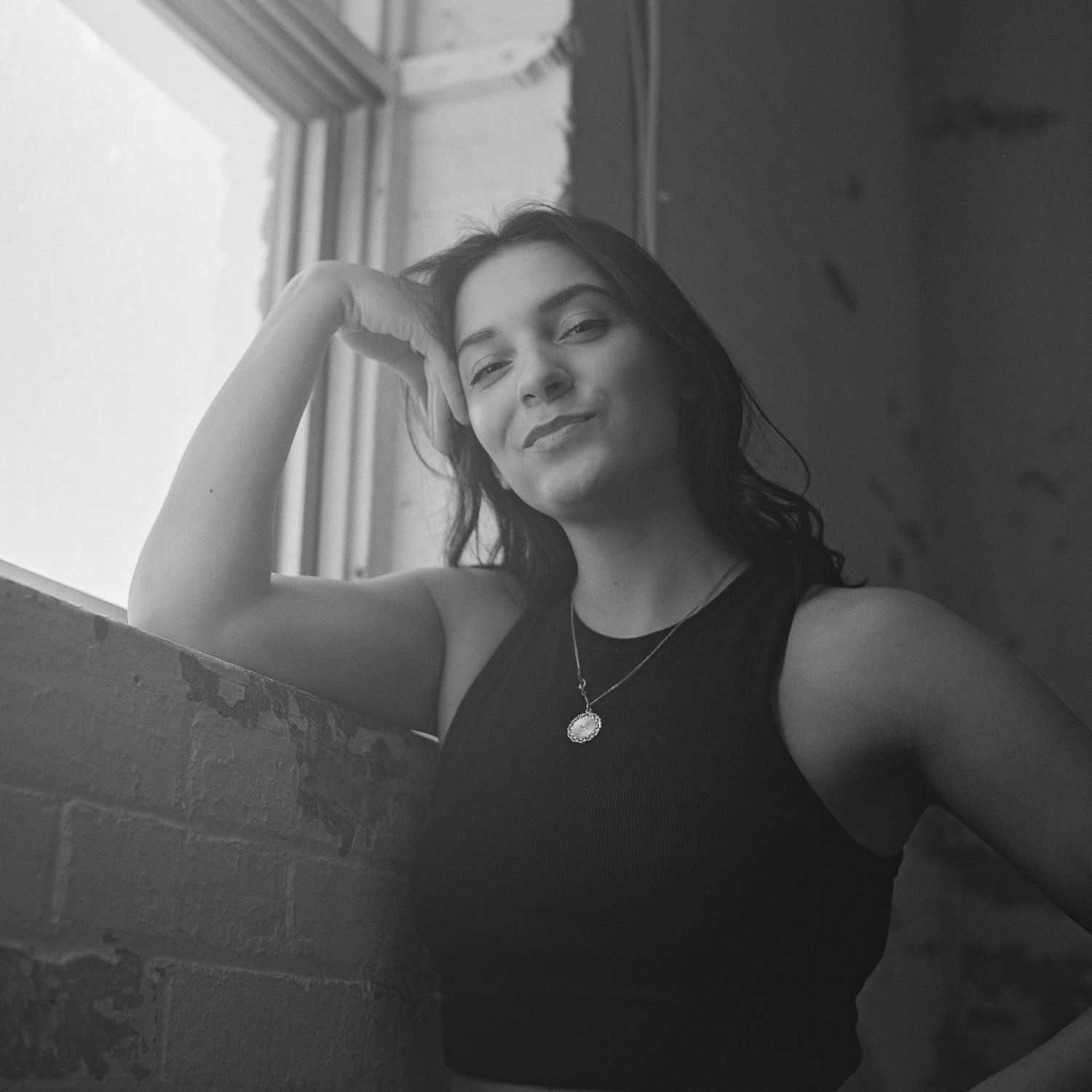 Black and white artistic portrait series showing dramatic poses and lighting against a window backdrop.