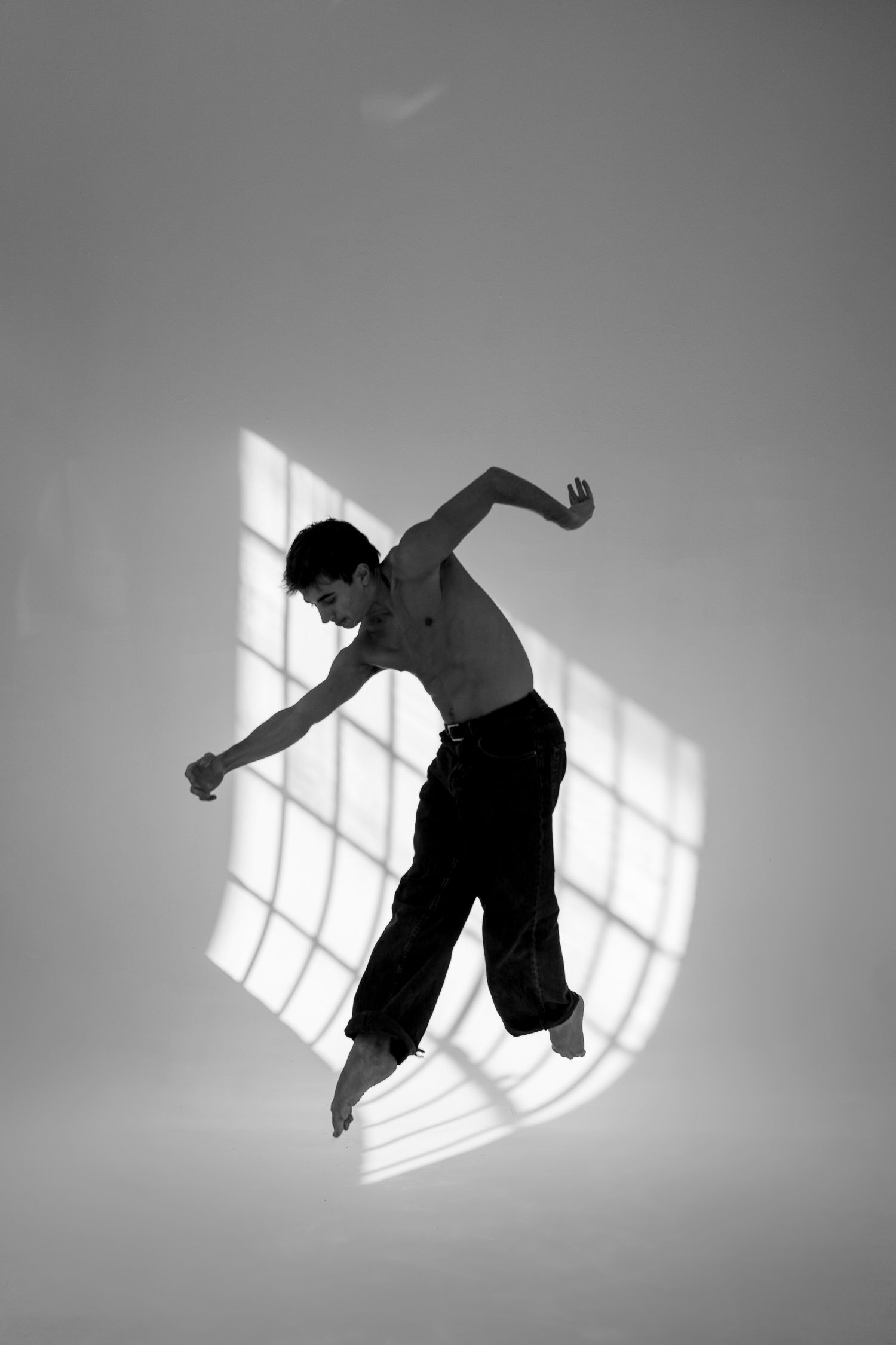 A sequence of black and white photos showing a person levitating or floating in front of a sunlit window.
