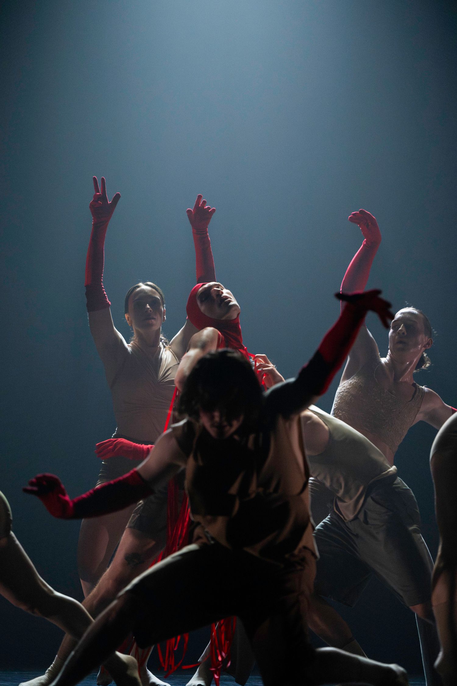 Silhouetted figures dance with raised arms against a dark background with dramatic lighting creating an energetic club atmosphere.