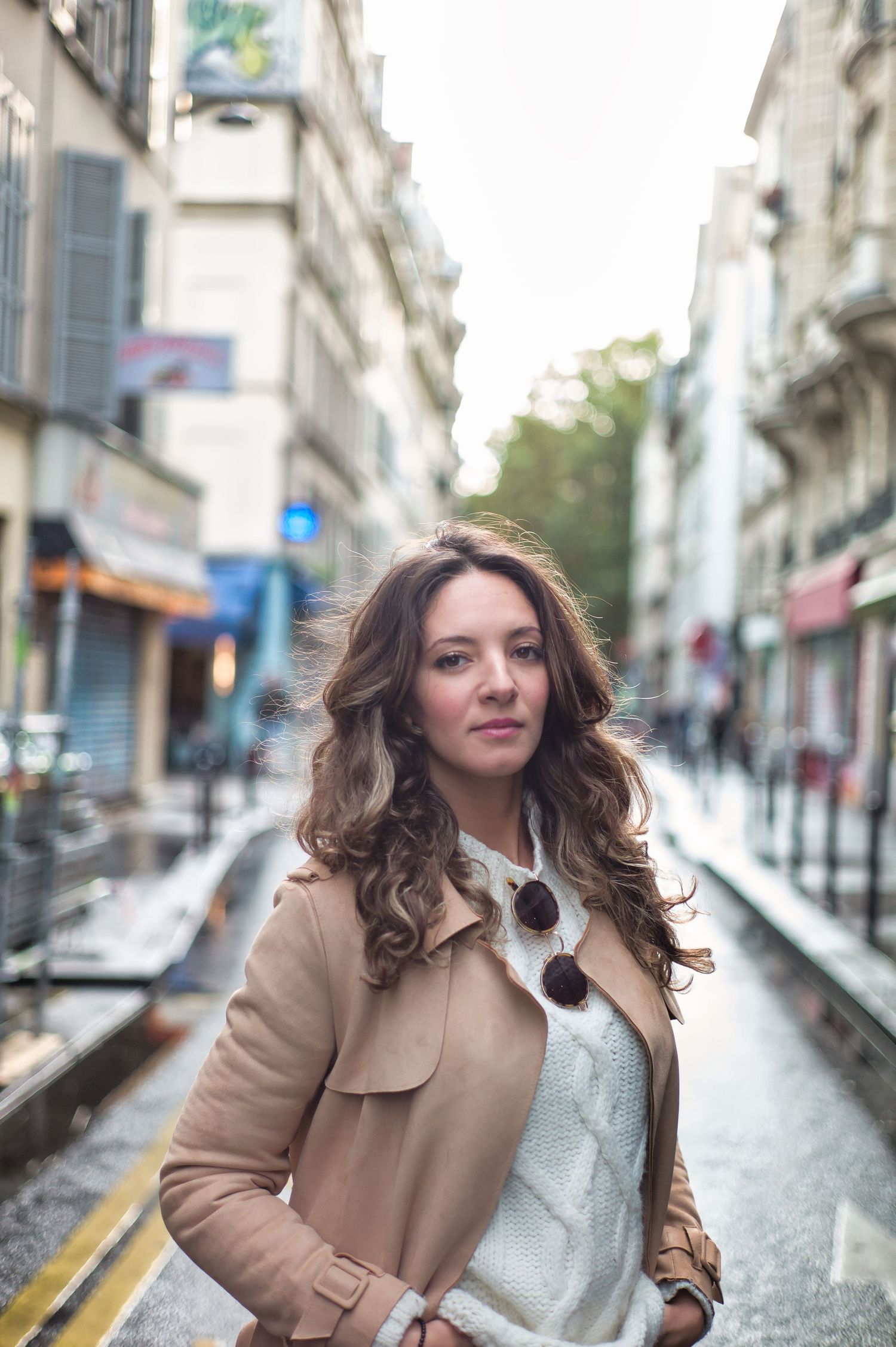 A young woman with curly hair in a beige coat poses on a Parisian street with blurred buildings.
Kenza Kassabi Tedx
Lotus Land.Photo