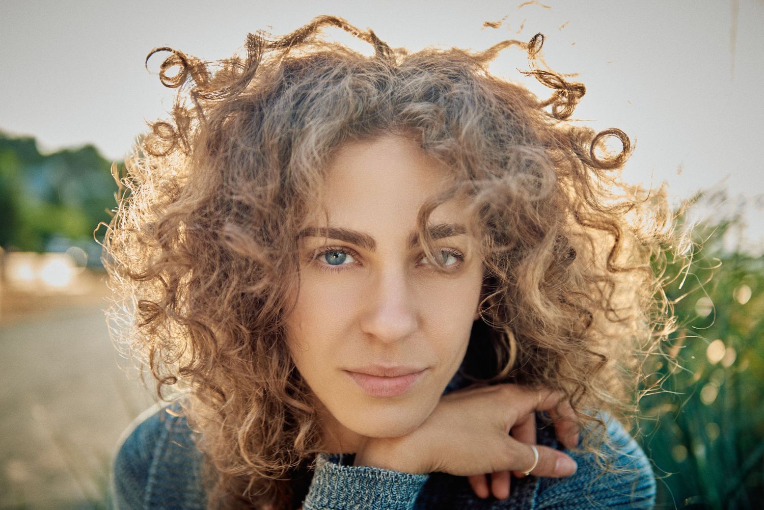 Young woman with curly blonde hair and blue eyes poses outdoors in soft golden sunlight.
Carmel Amit
Actress
Lotus Land.Photo