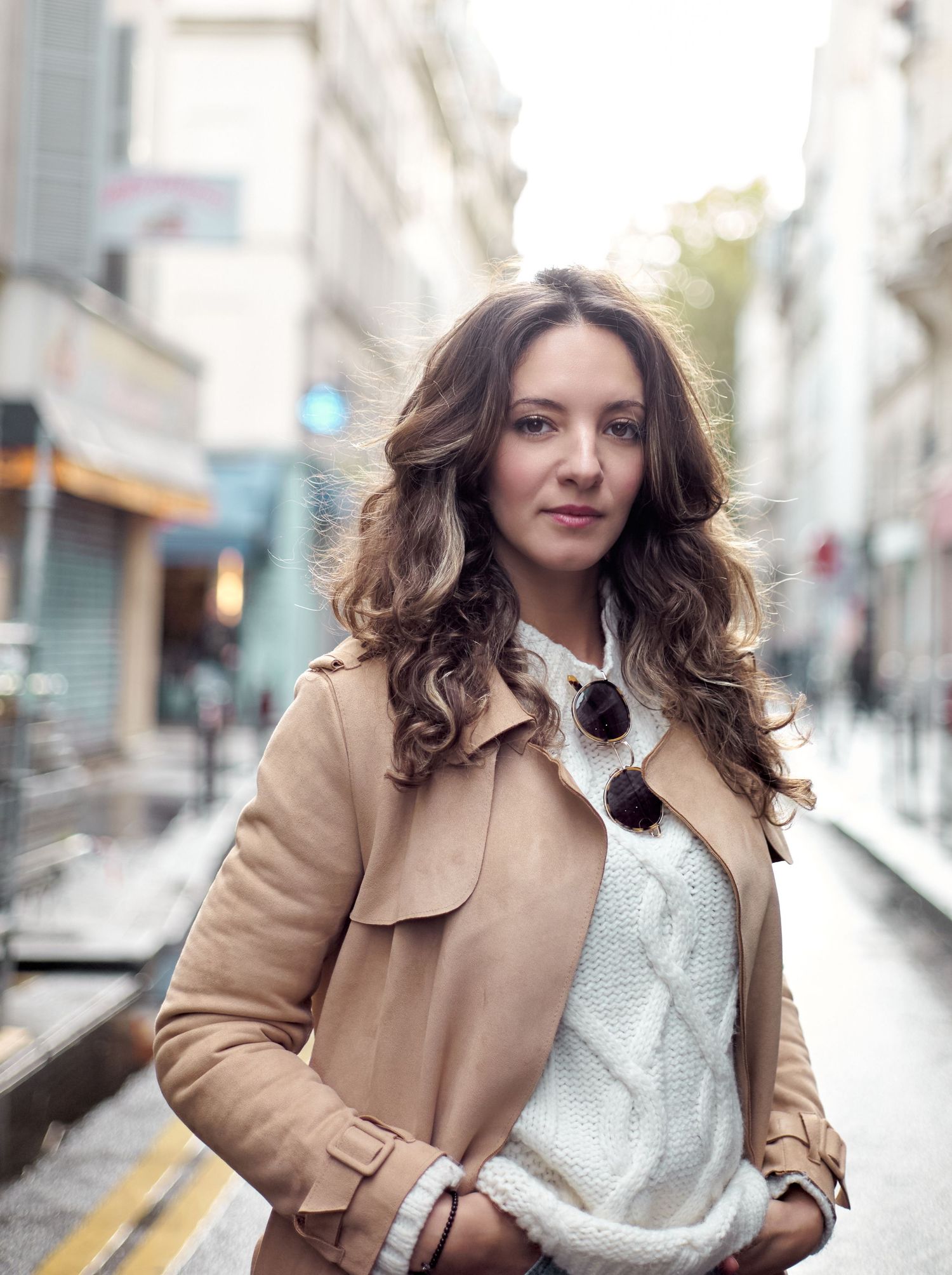 Young woman with curly brown hair wearing a beige trench coat white sweater in an European city street.
Kenza Kassabi Tedx
Lotus Land.Photo