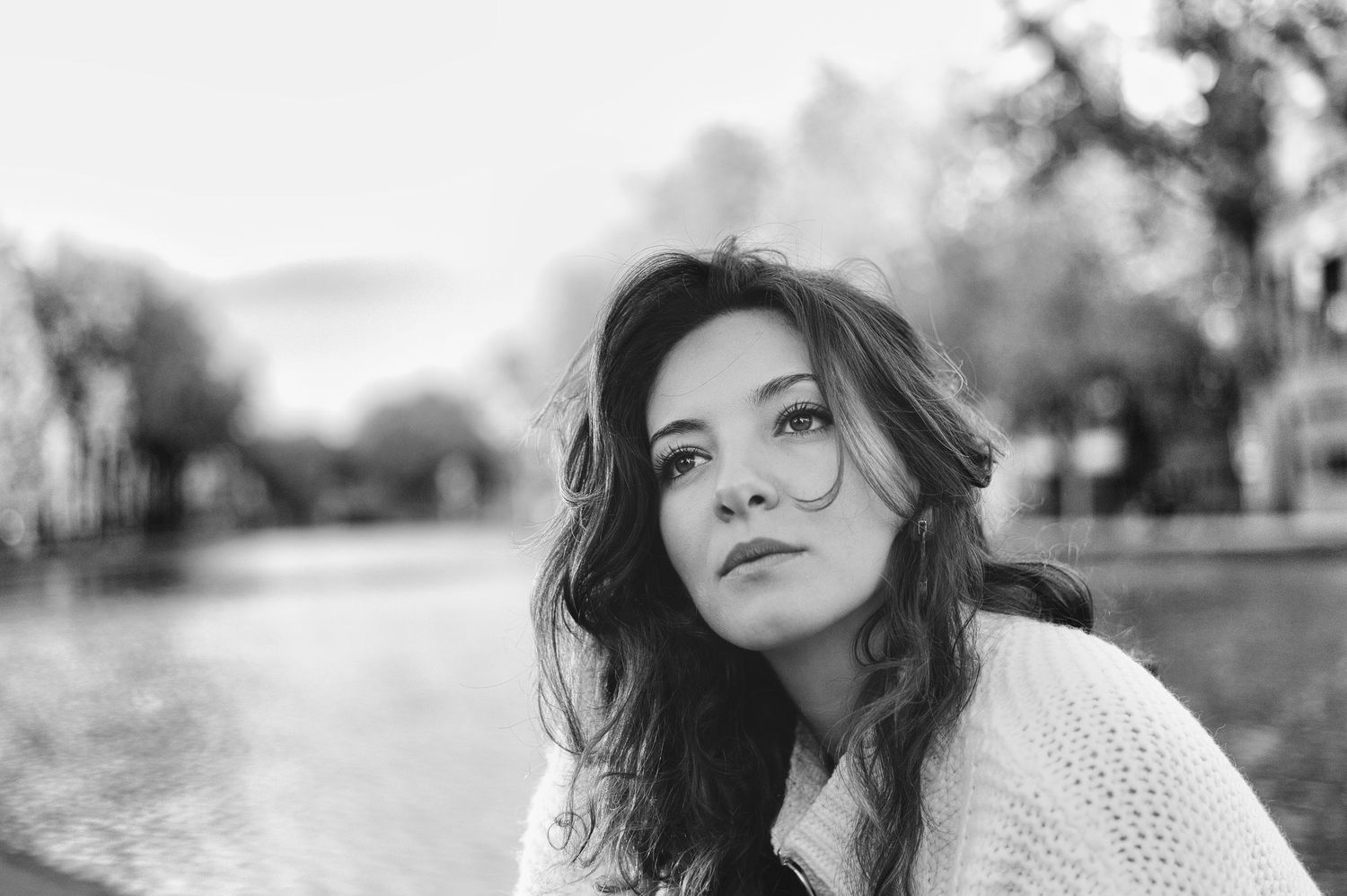 Black and white portrait of a young woman with wavy hair sitting near a lake in a outdoor setting.
Kenza Kassabi Tedx
Lotus Land.Photo