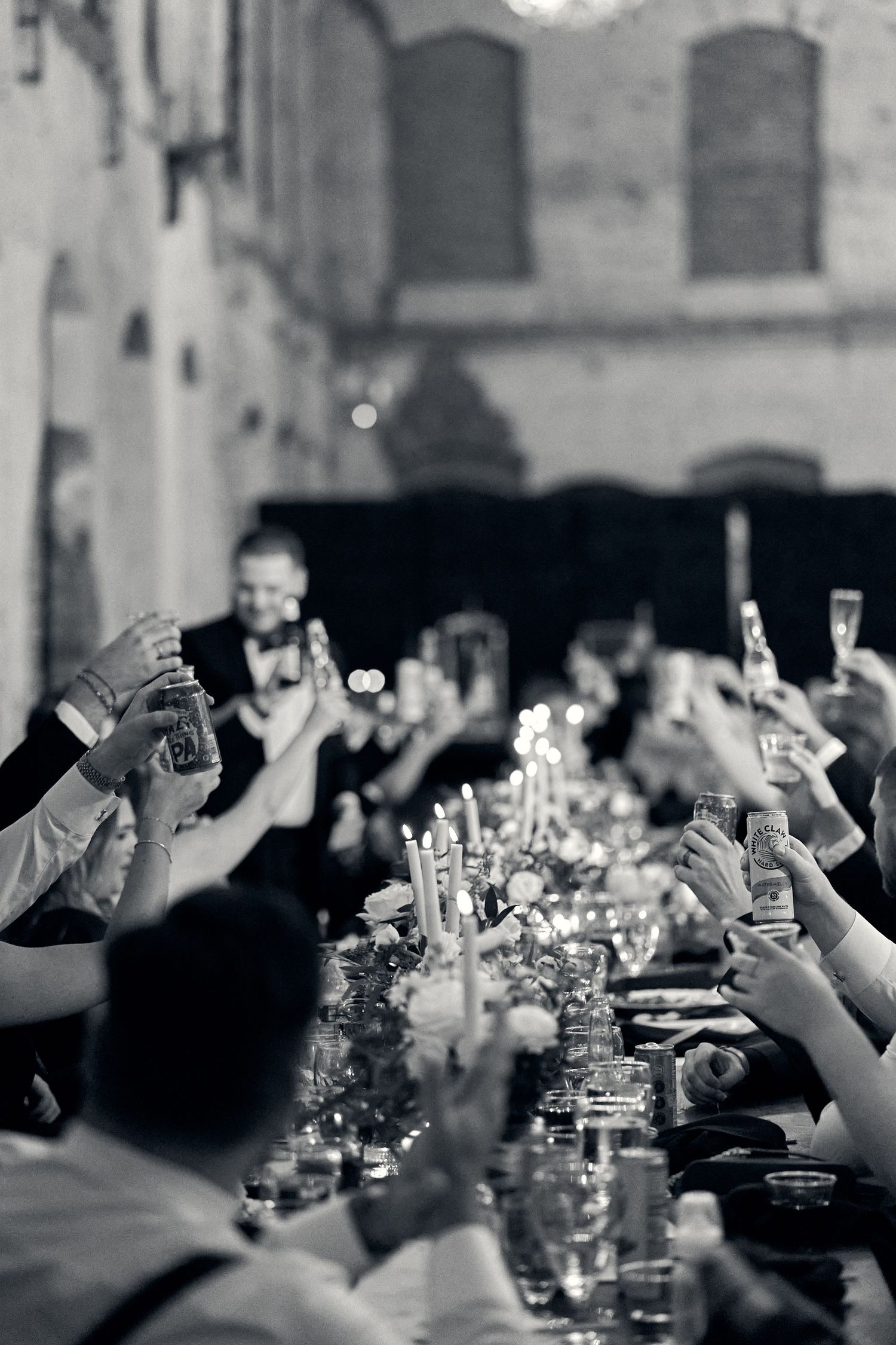 Wedding guests raise their glasses in a toast during an elegant black and white reception dinner.