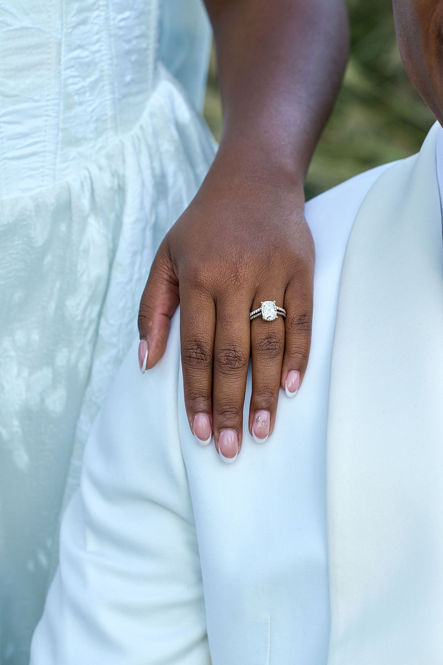 Close-up of bride's hand showing a stunning emerald-cut diamond engagement ring on her wedding day.