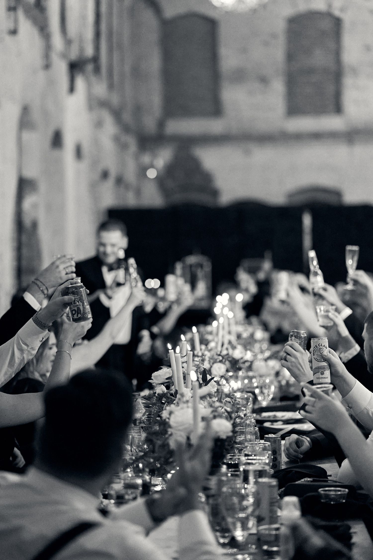 Wedding guests raise glasses in a champagne toast at an elegant candlelit reception. North Carolina Wedding Photographer.