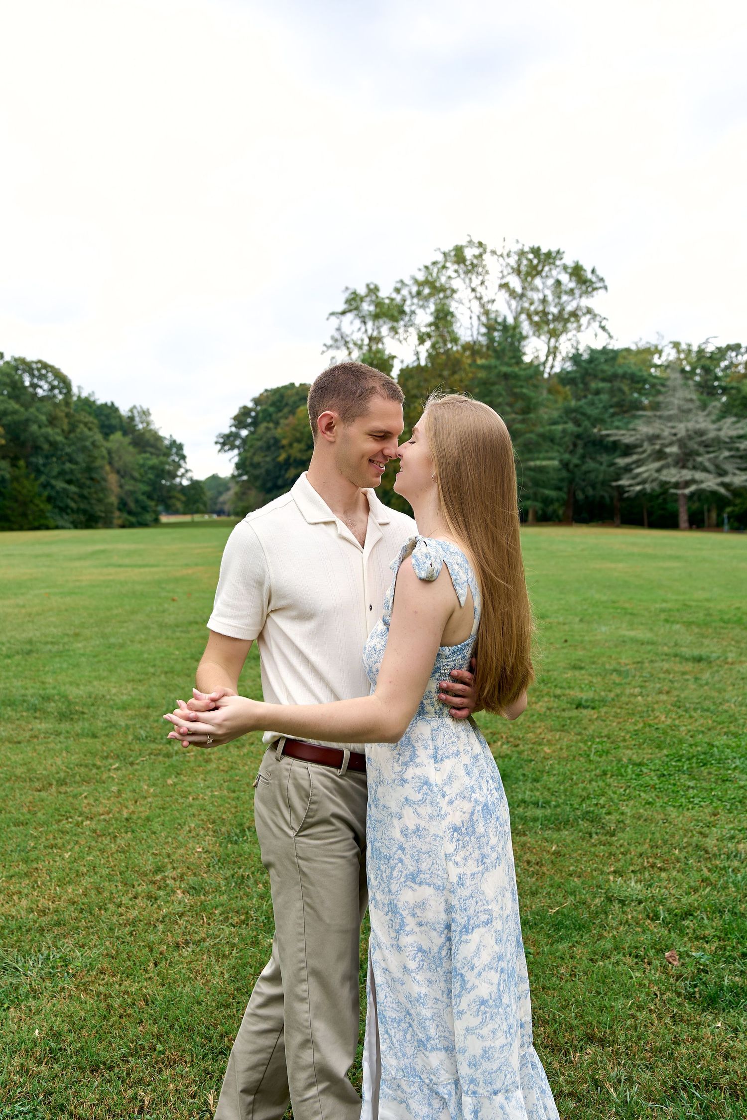 A couple shares tender moments while standing in a green open field. North Carolina Wedding Photographer.
