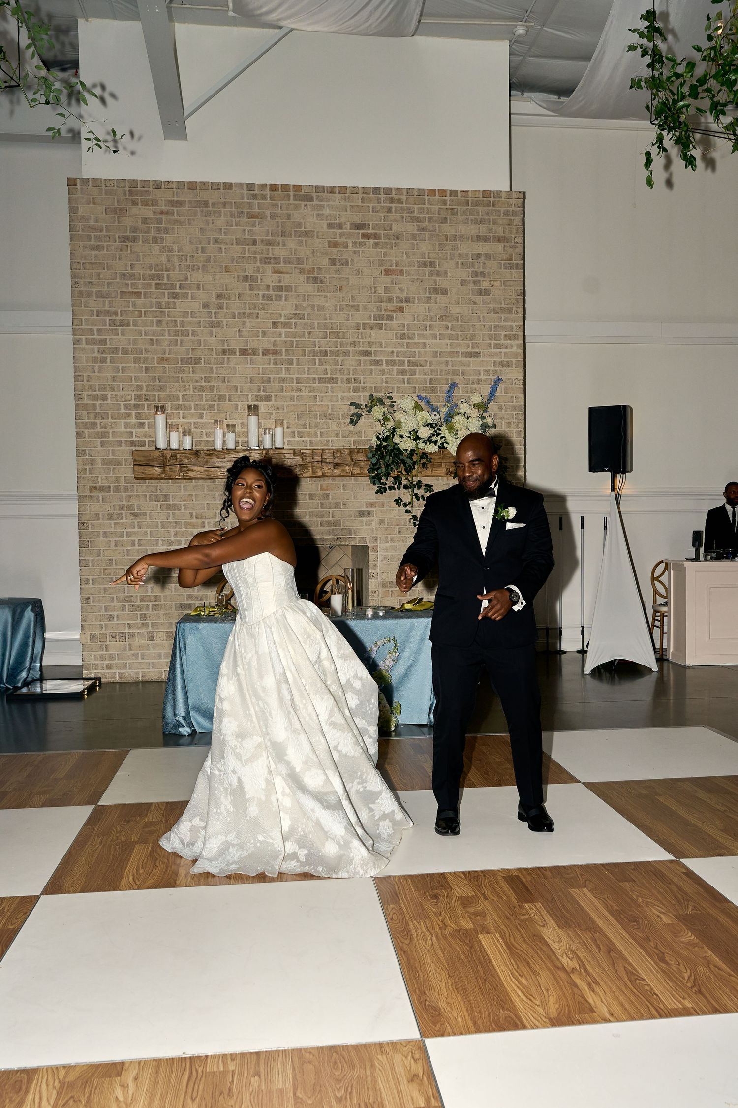 Bride and groom share their first dance on a checkered dance floor at an elegant wedding reception.