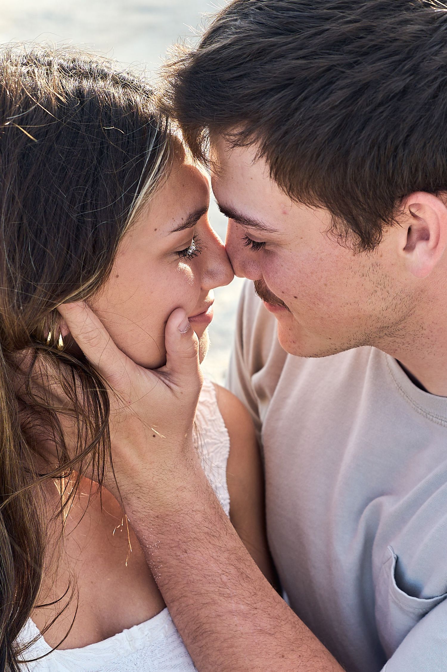 Young couple sharing an intimate moment as they lean in close to each other, smiling and touching foreheads.