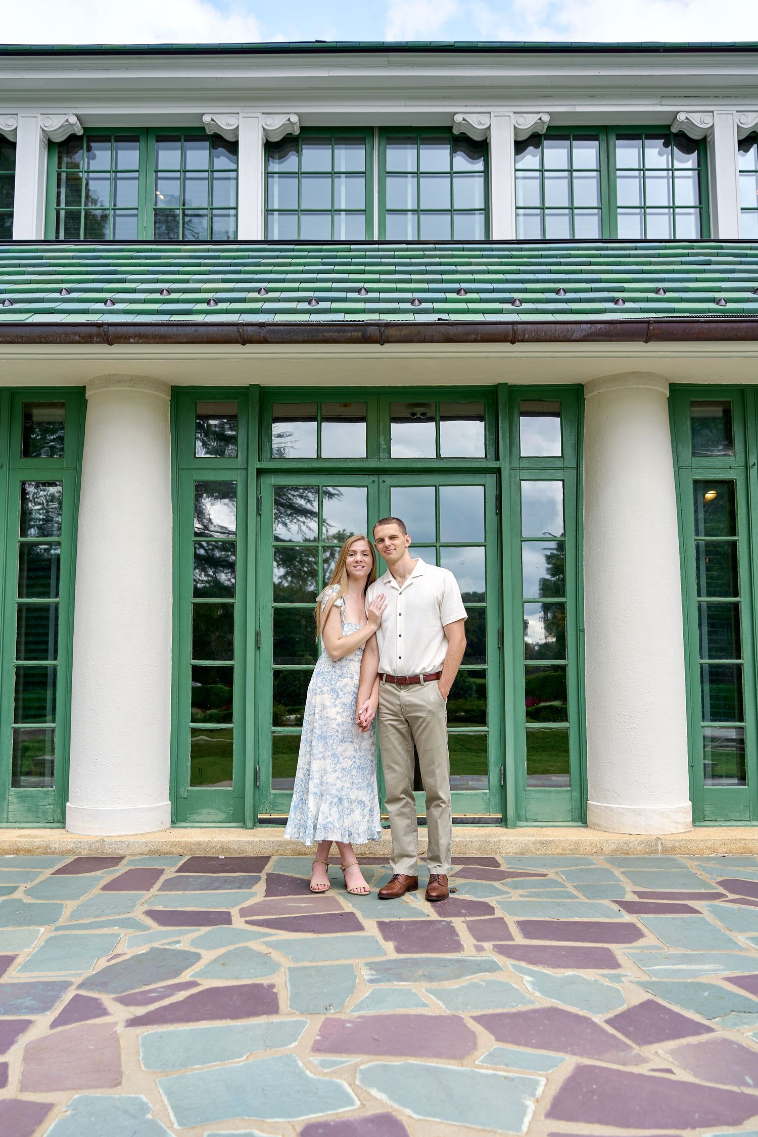 A colonial building with green trim features stone tile flooring and white columns along its facade. North Carolina Wedding Photographer.