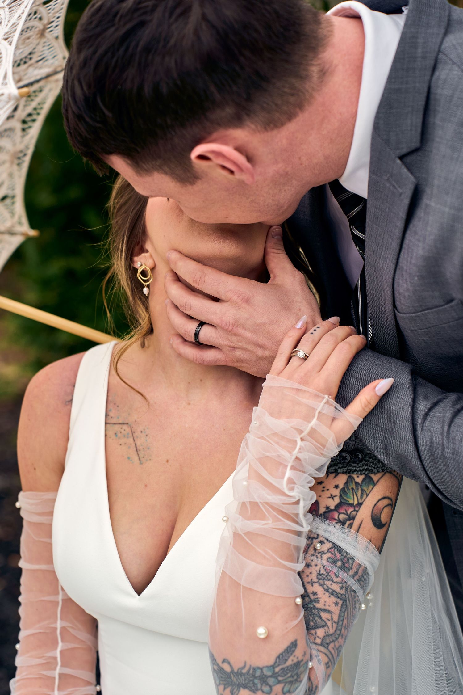 Romantic wedding photo showing intimate moment between couple with bride in white dress and detailed tattoo sleeve.