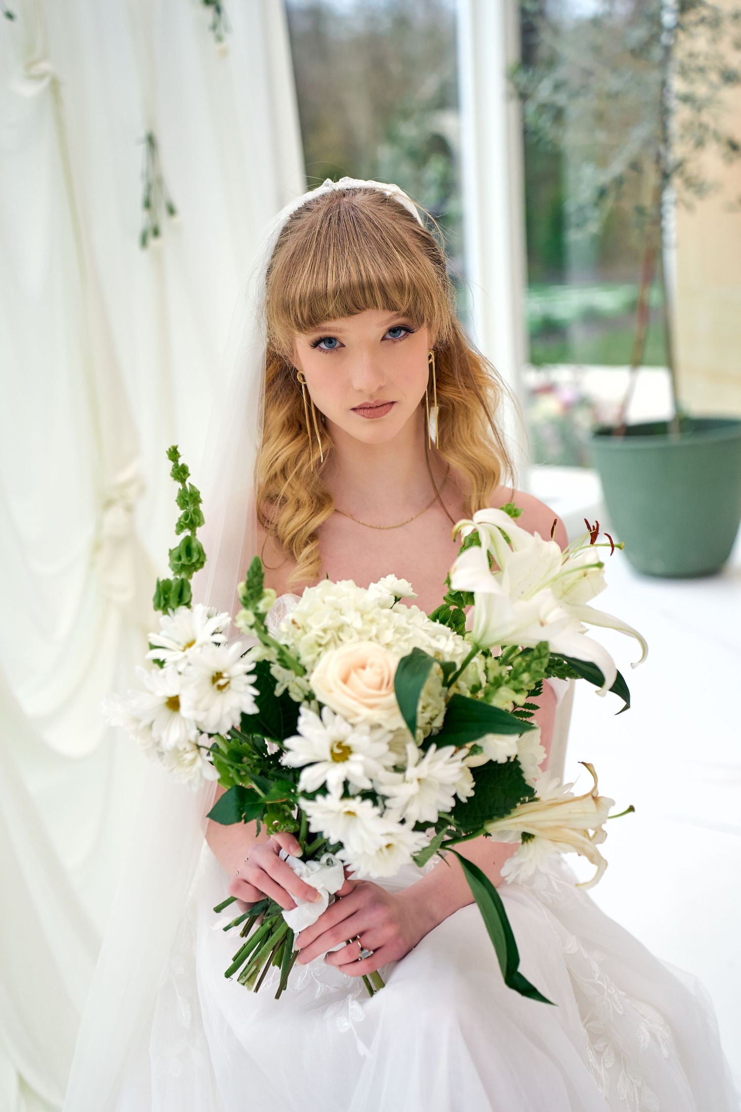 A bride in a white gown holds a stunning bouquet of white lilies and cream roses against a soft, elegant background.