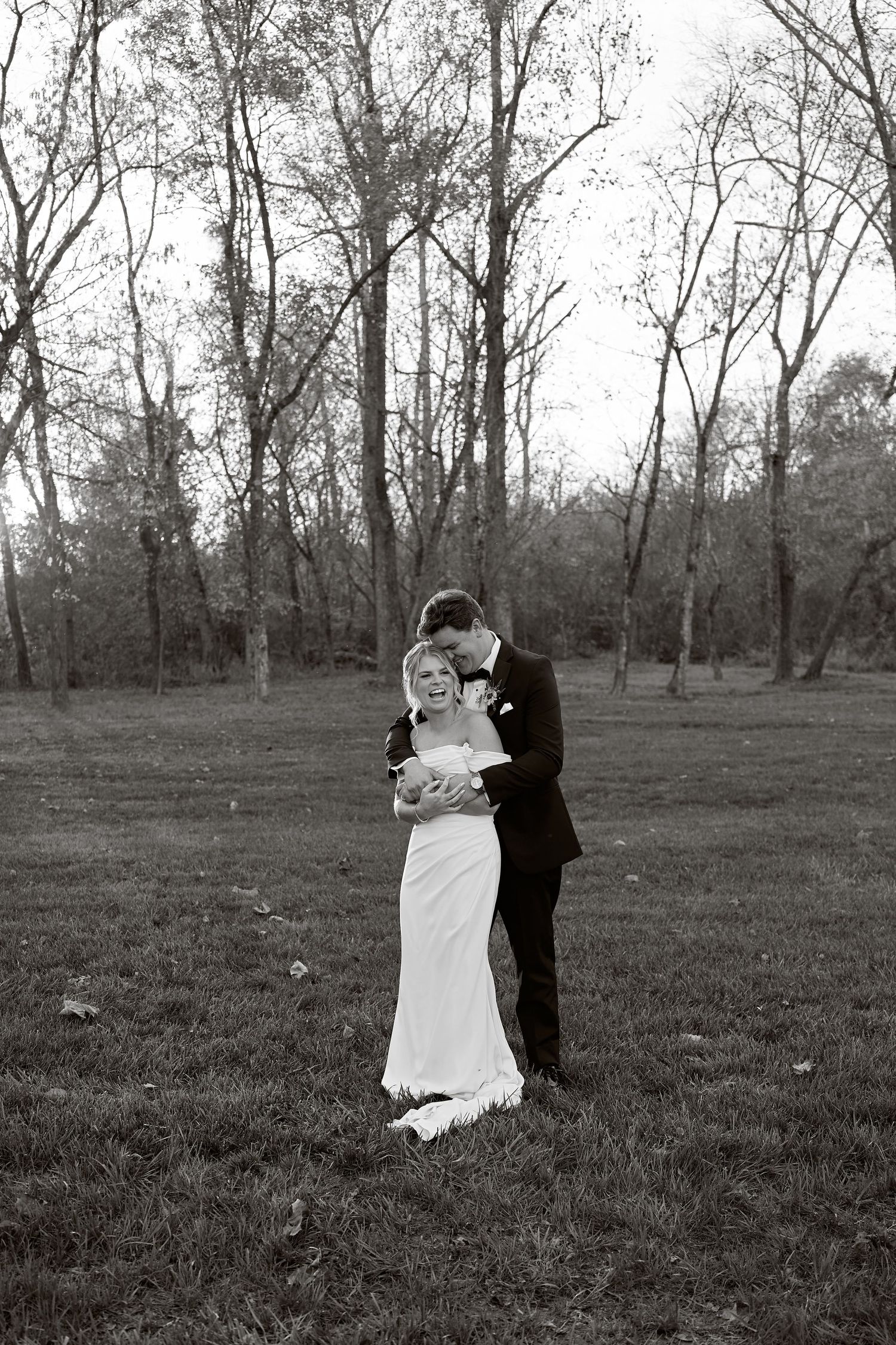 Black and white portrait of groom tenderly embracing bride in an open autumn field. North Carolina Wedding Photographer.
