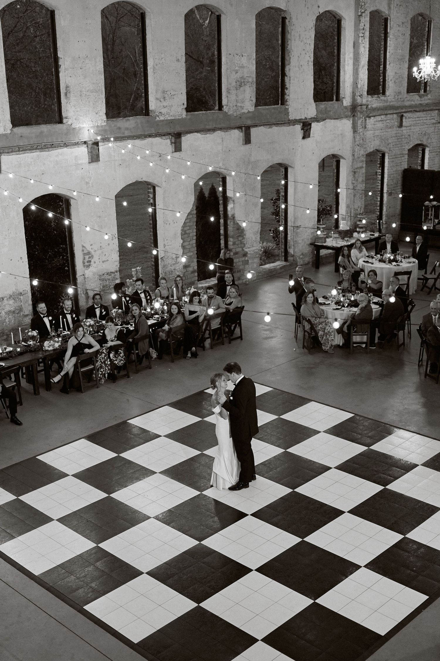 Aerial black and white view of couple sharing first dance on checkered ballroom floor. North Carolina Wedding Photographer.