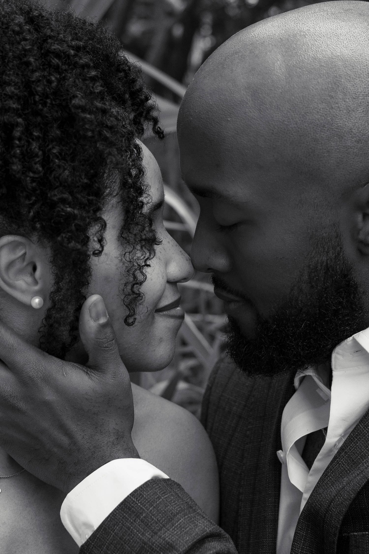 Intimate black and white portrait of couple nearly kissing, man cradling woman's face tenderly.