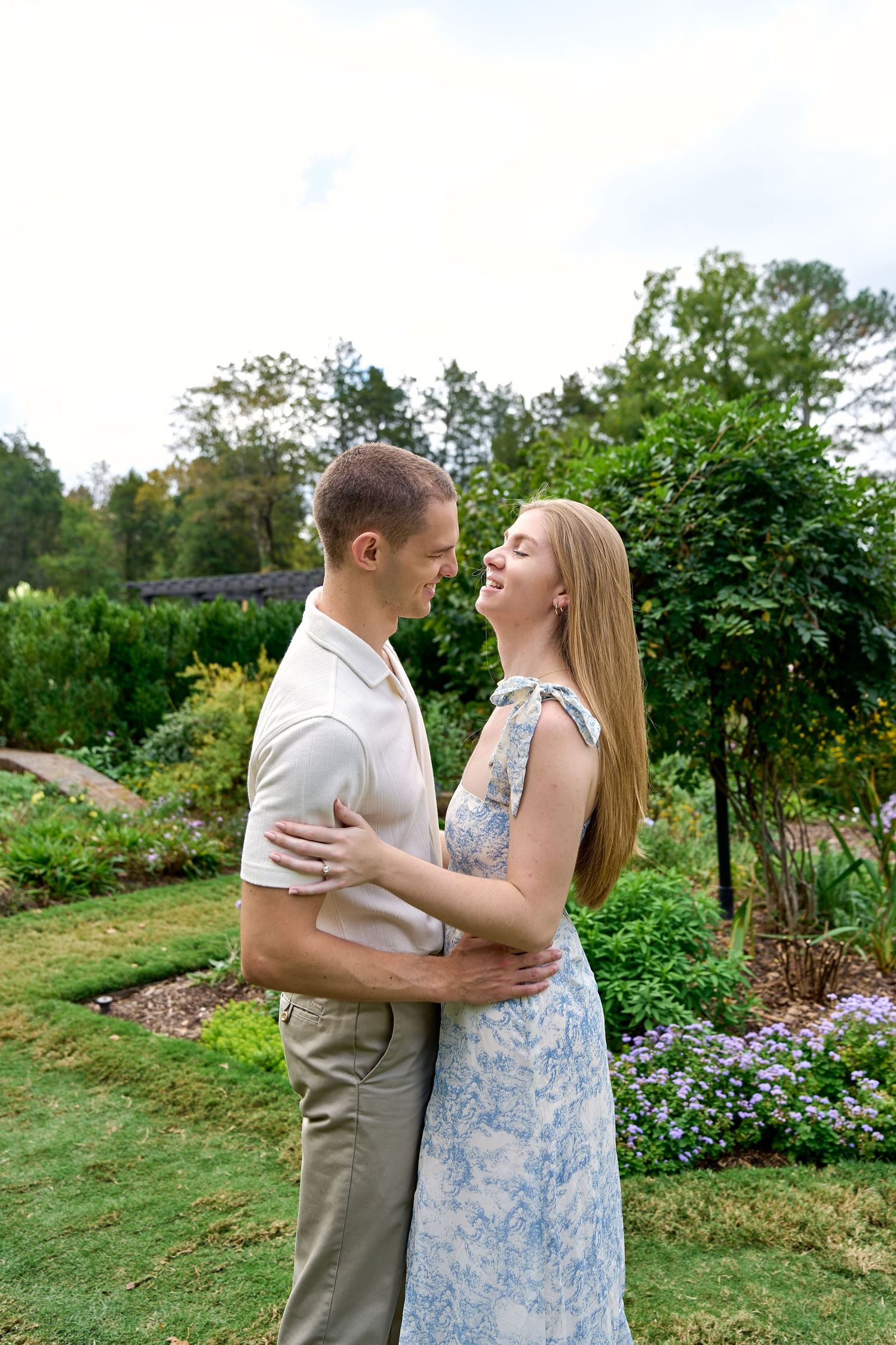 A couple shares an intimate embrace in a garden setting with blooming flowers and greenery. North Carolina Wedding Photographer.