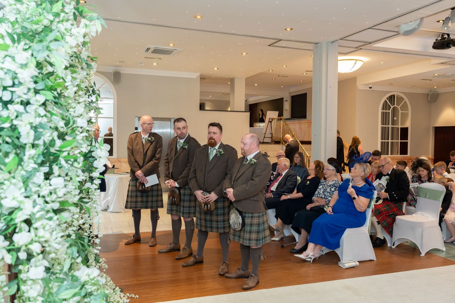 Groomsmen in kilts standing at the altar awaiting the bride at a wedding ceremony.