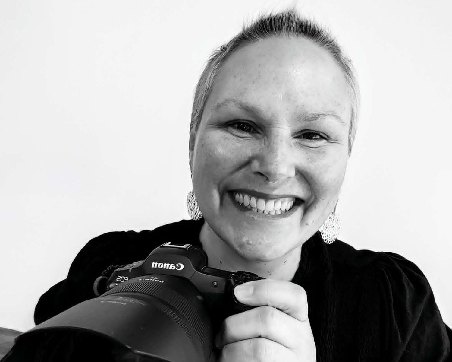 Claire House from Claire House Photography smiling, holding a Canon camera.