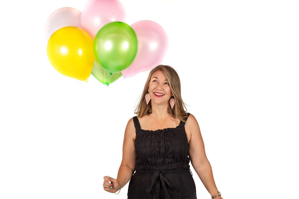 Claire House Photography studio photograph of a business woman holding balloons and smiling.