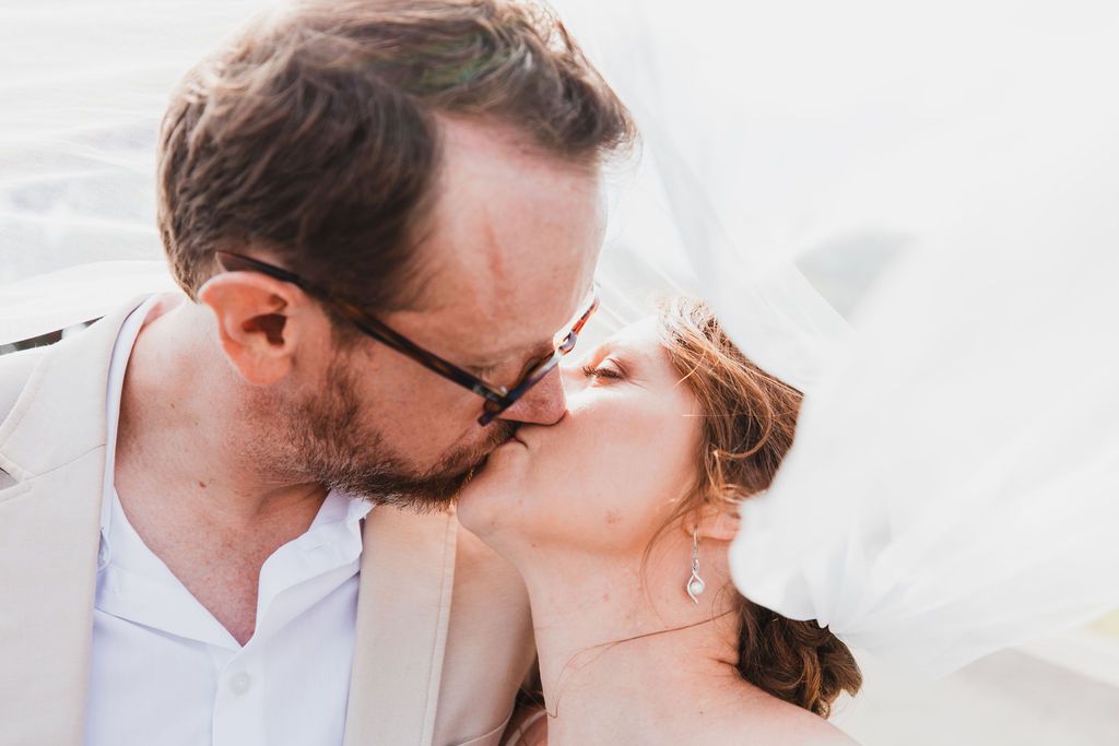 Claire House Photography social and wedding event photograph of a husband and wife kissing under her veil.