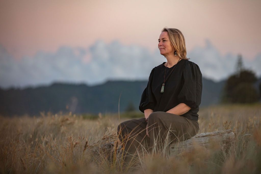 Claire House Photograph business photograph of a woman sitting in the dunes at sunset.