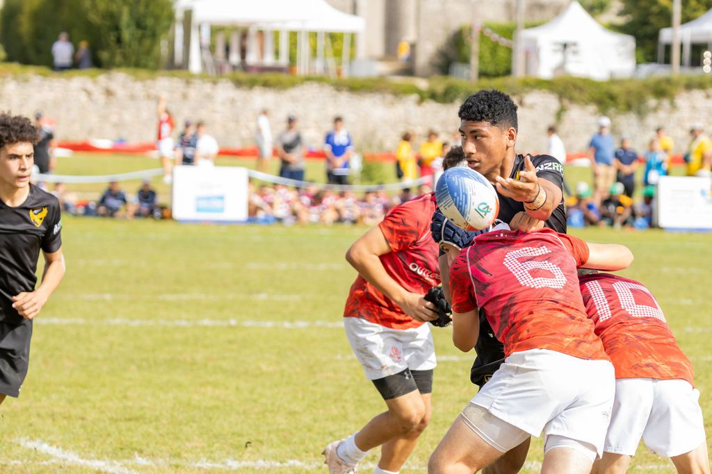 Claire House Photography sports event photograph of a boy offloading a rugby ball while being tackled in sevens rugby.
