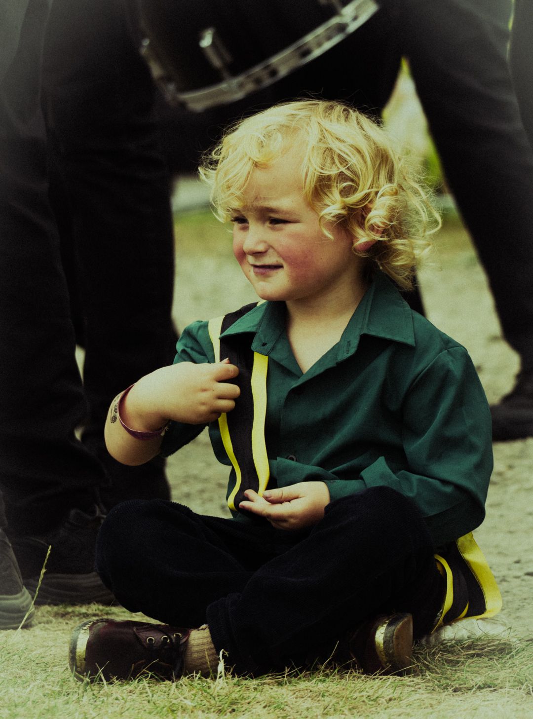 young boy sat on ground holding a musical instrument