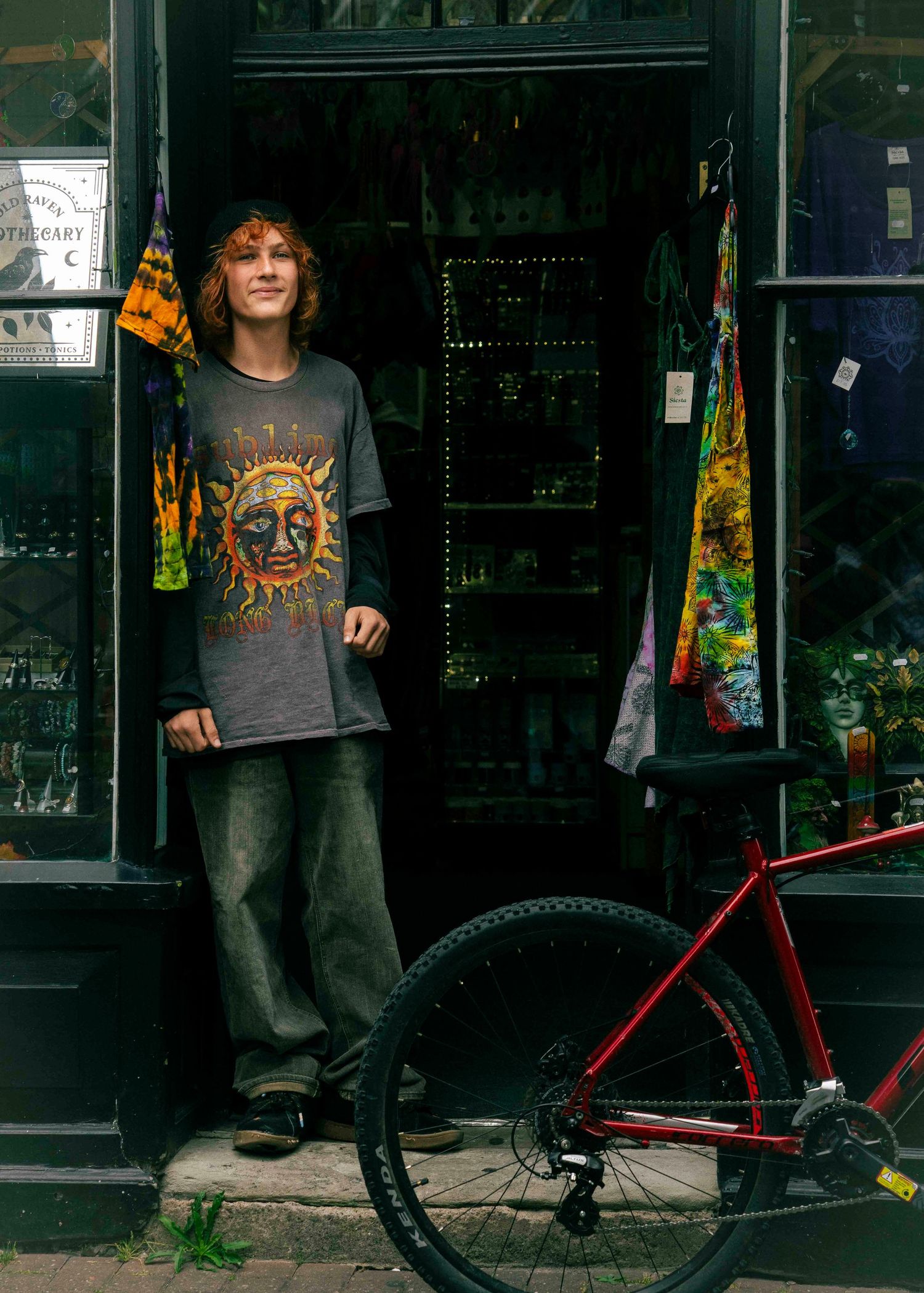 Young man stood in shop doorway with bicycle propped against door