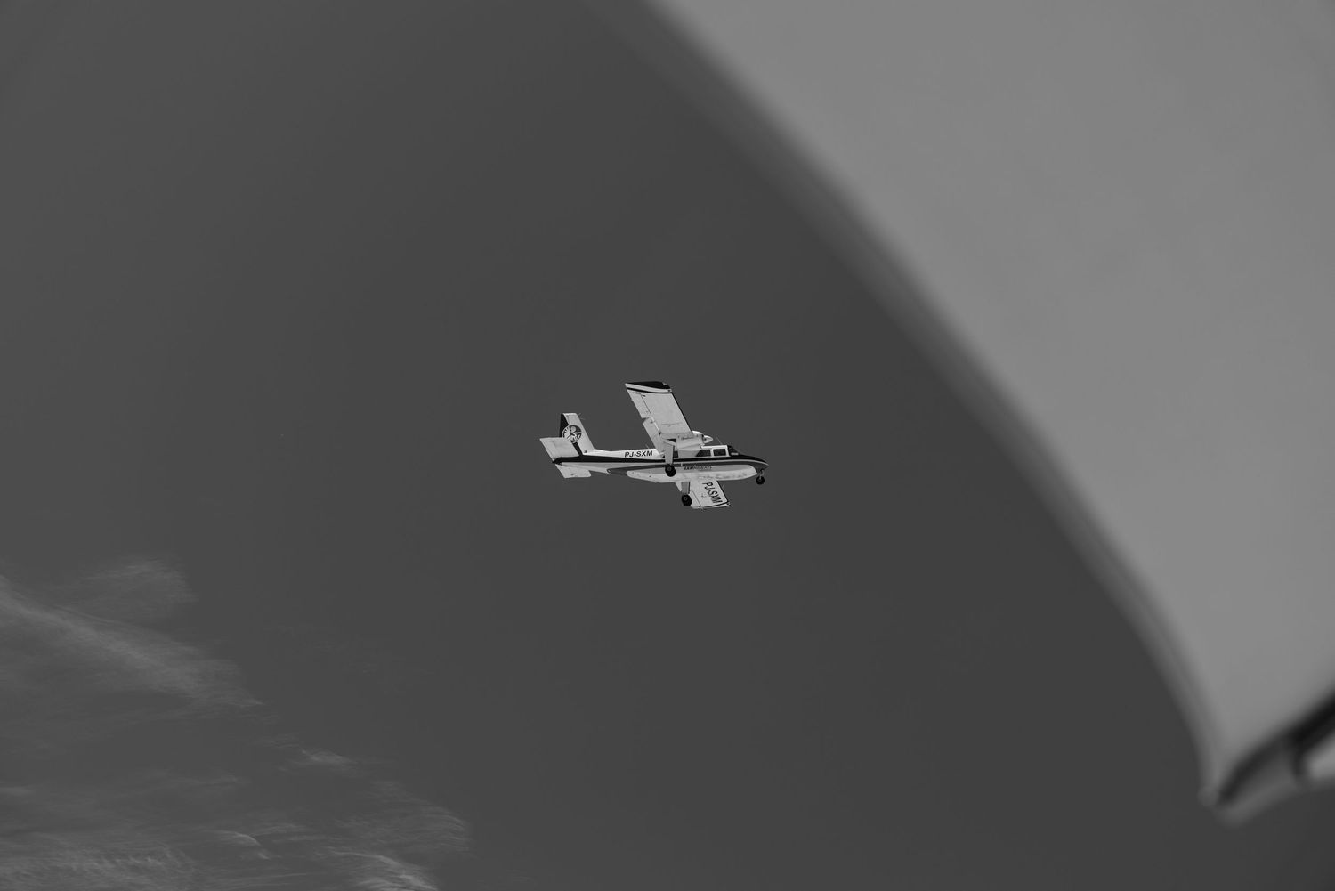 Small propeller airplane flying against a dramatic black and white cloudy sky.