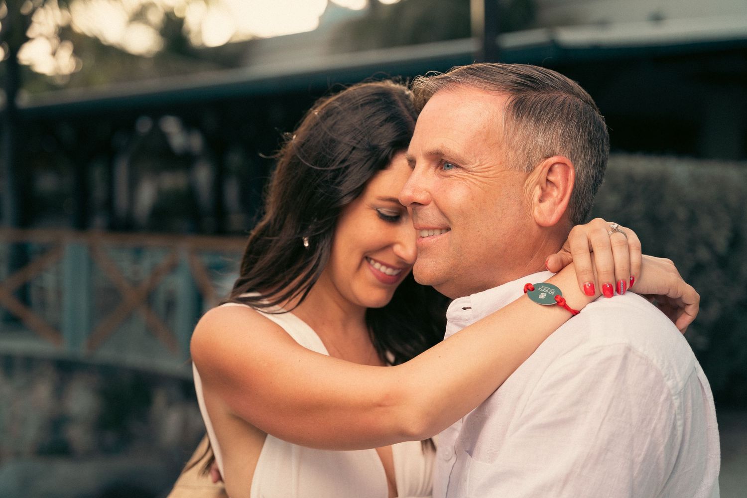 Affectionate couple embracing and smiling closely together outdoors in warm evening light.
