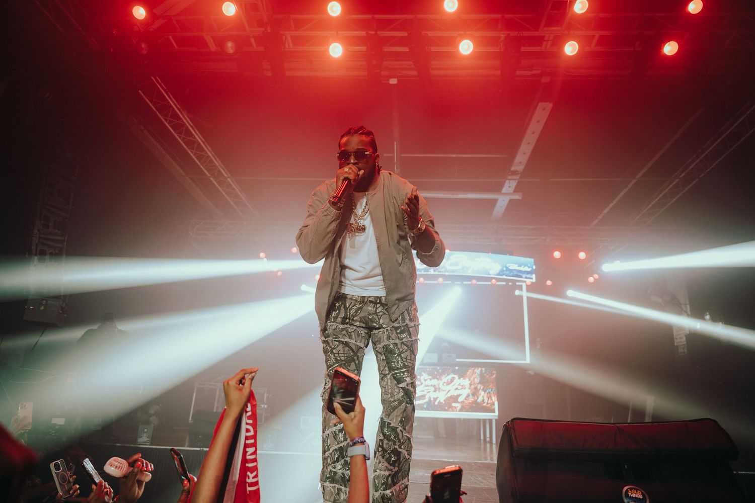 Performer on stage under red and white lights at a live concert event.