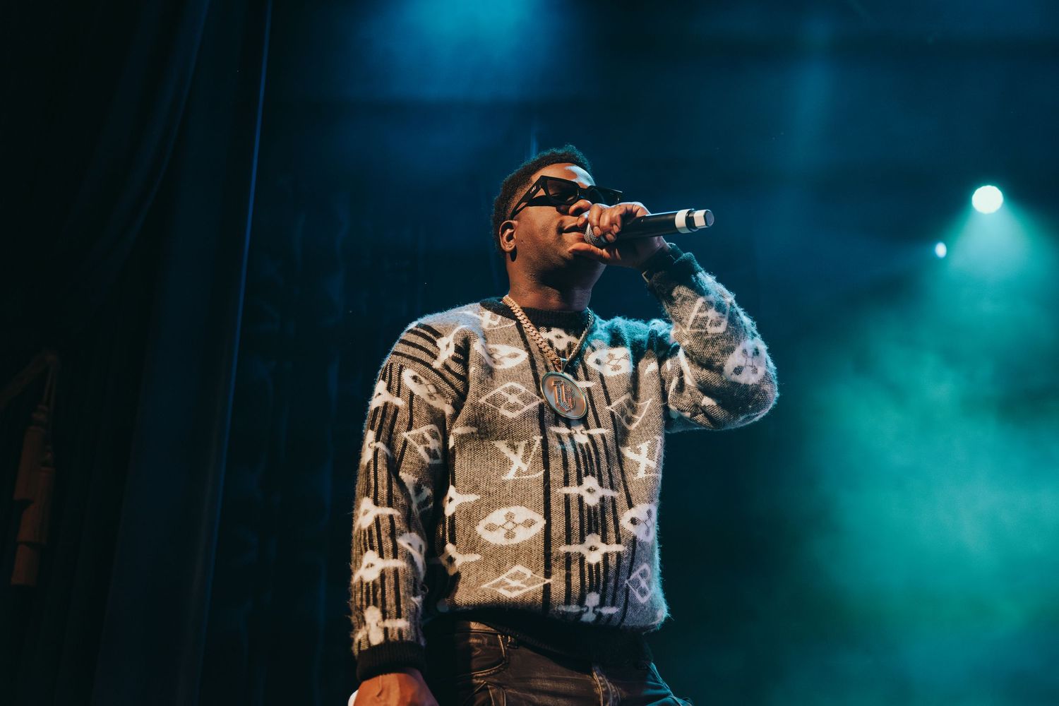 A male artiste performing on stage with a microphone at a concert.