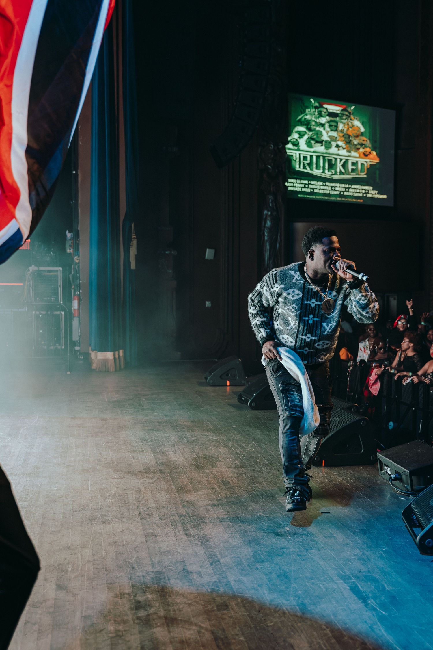 A male artiste performing on a smoky stage at a Soca concert event.