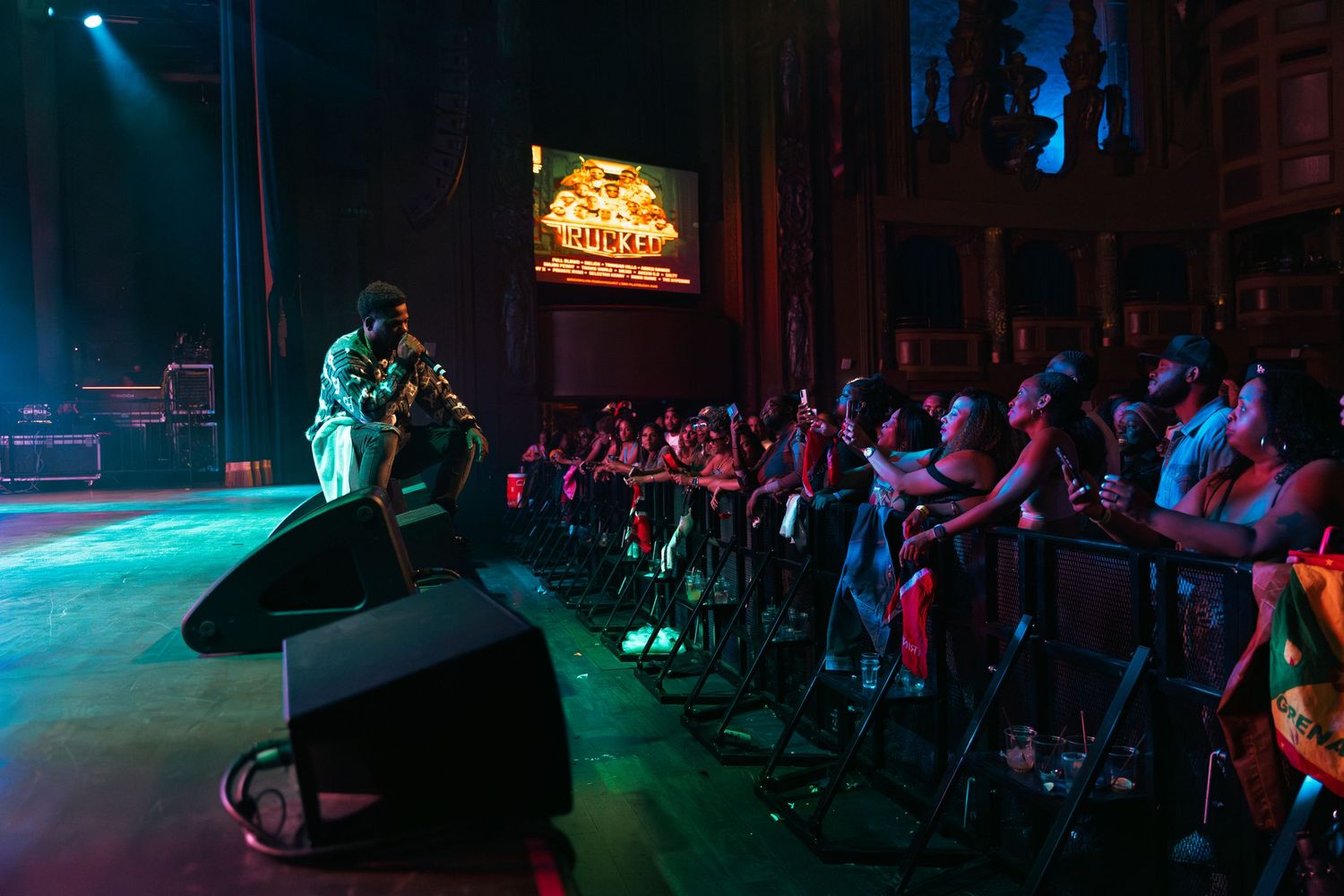 A performer engaging with the crowd at a packed indoor concert venue.
