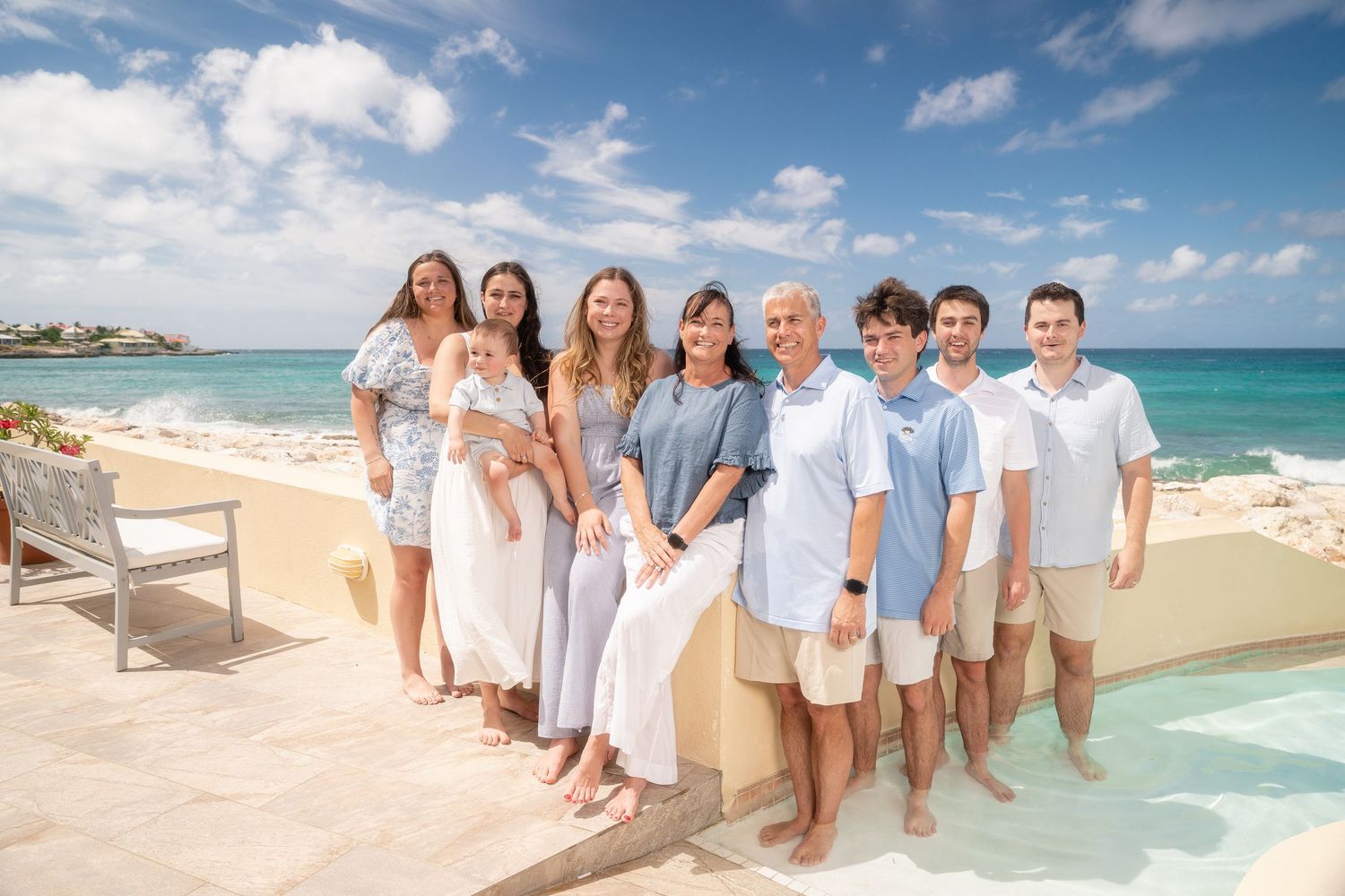 Large family group posing together by infinity pool with stunning ocean backdrop.