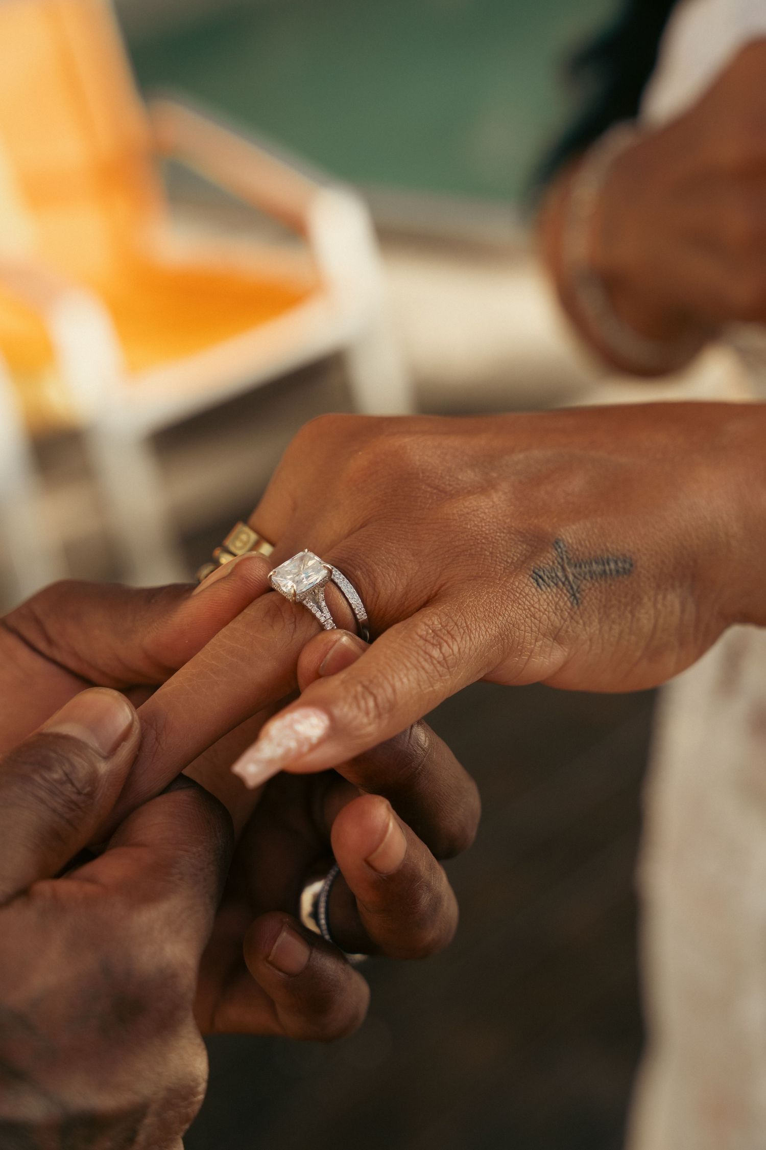 Close-up of groom placing diamond engagement ring on bride's finger during wedding ceremony.