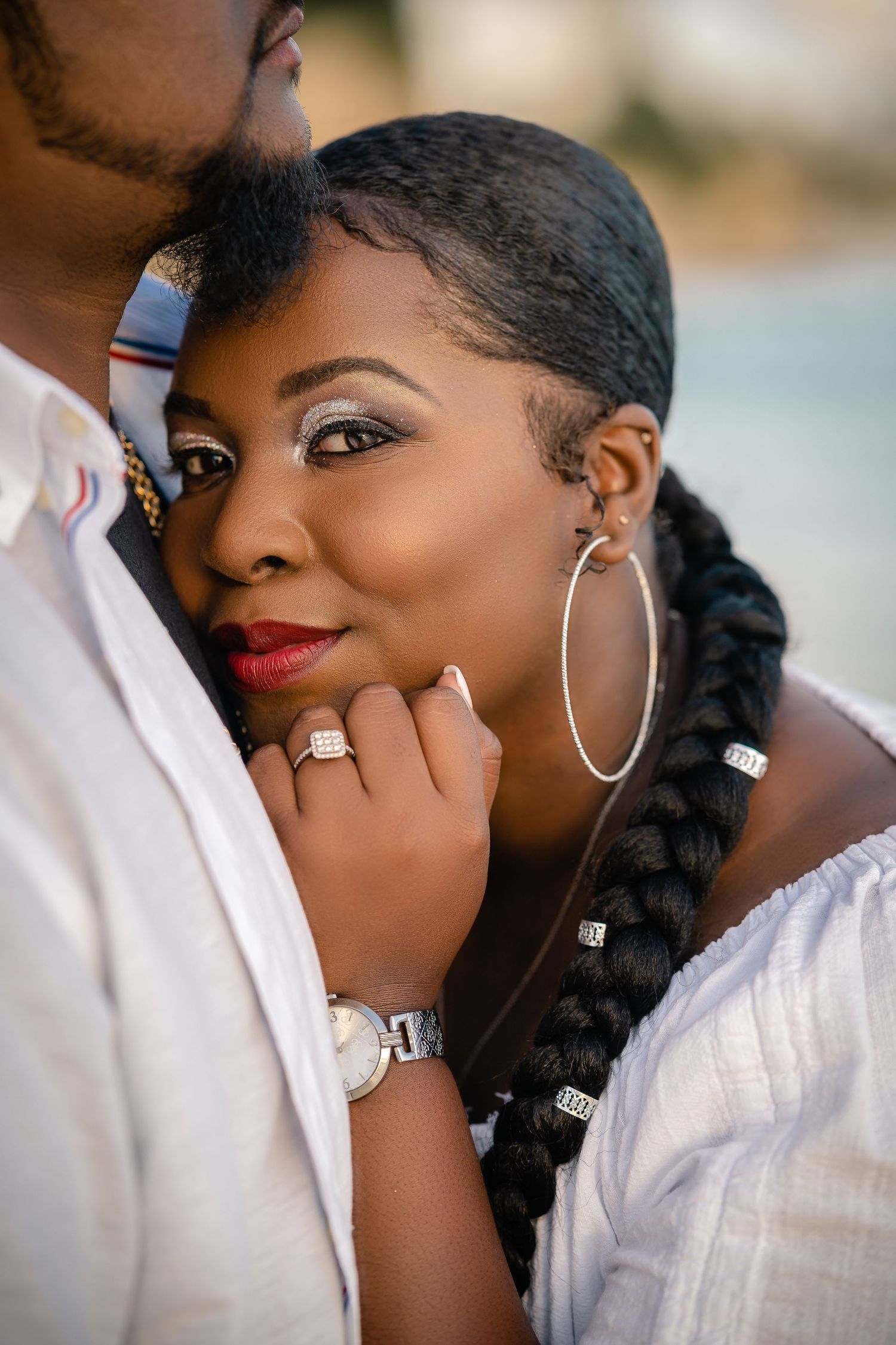 Elegant Black woman leaning on partner showing diamond engagement ring and watch.