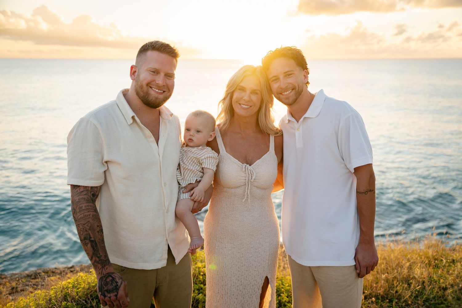 Family of four posing at ocean overlook during stunning golden sunset.