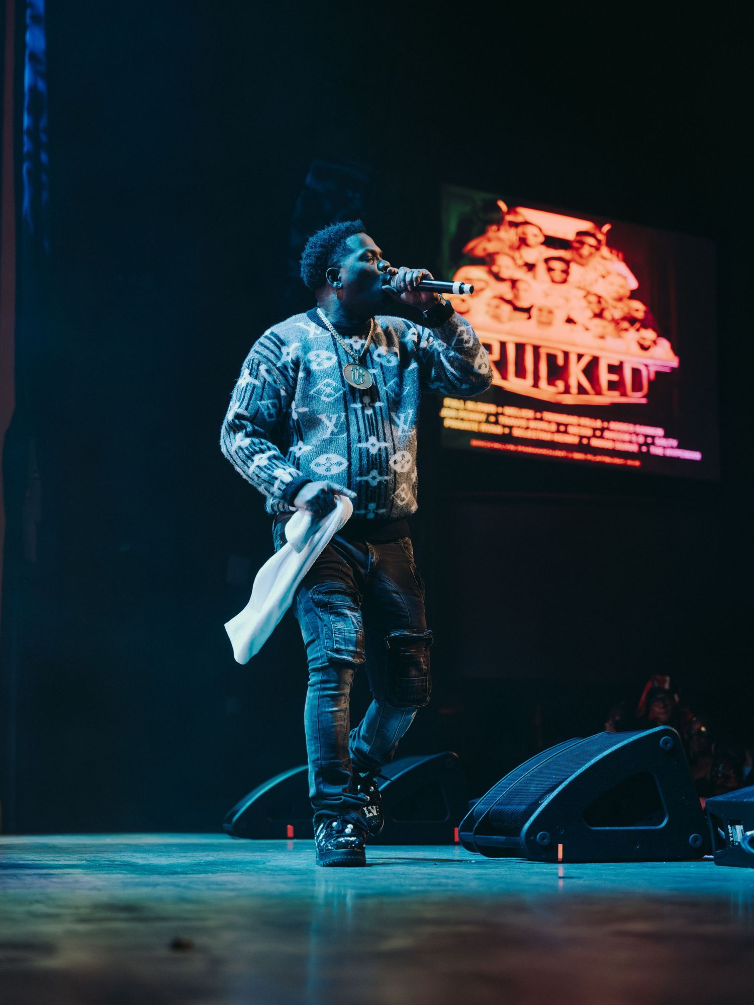 A male artist performing on stage with a microphone at a soca concert.