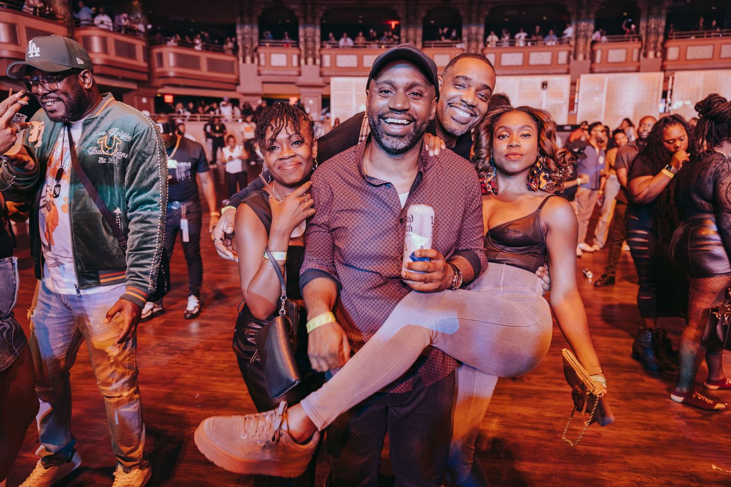 Group of friends posing and smiling together at a vibrant indoor concert venue.