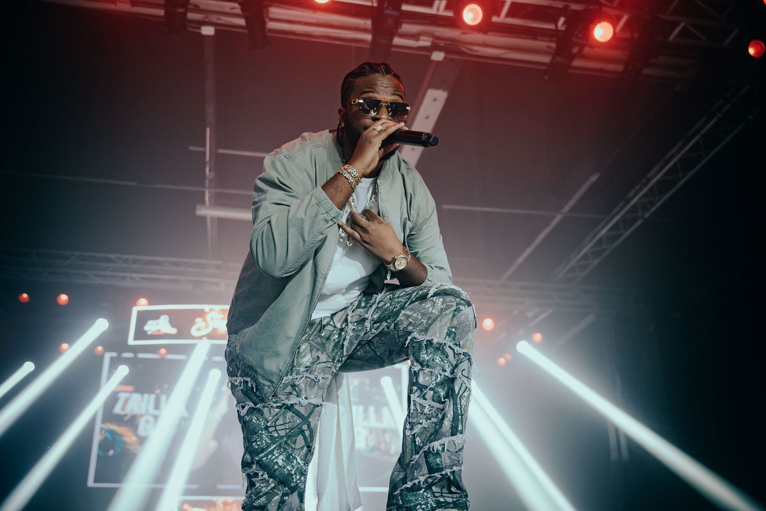 Male artist performing on stage in patterned pants under bright spotlights.