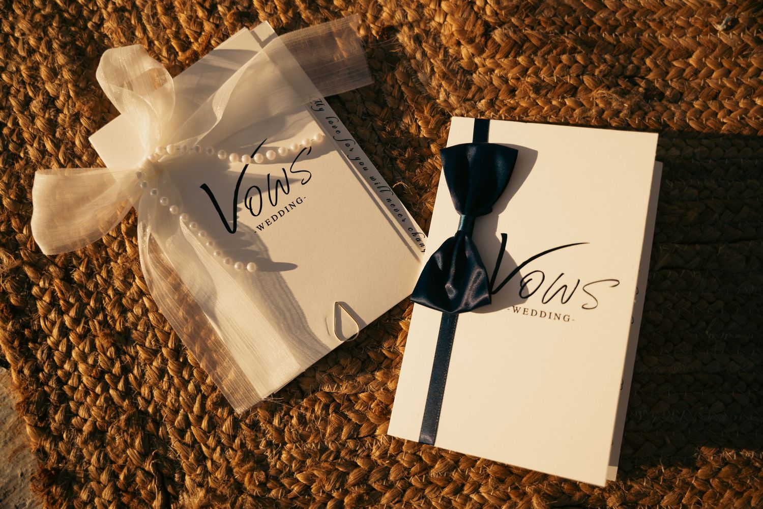 Elegant wedding vow booklets tied with ribbon displayed on textured golden fabric.
