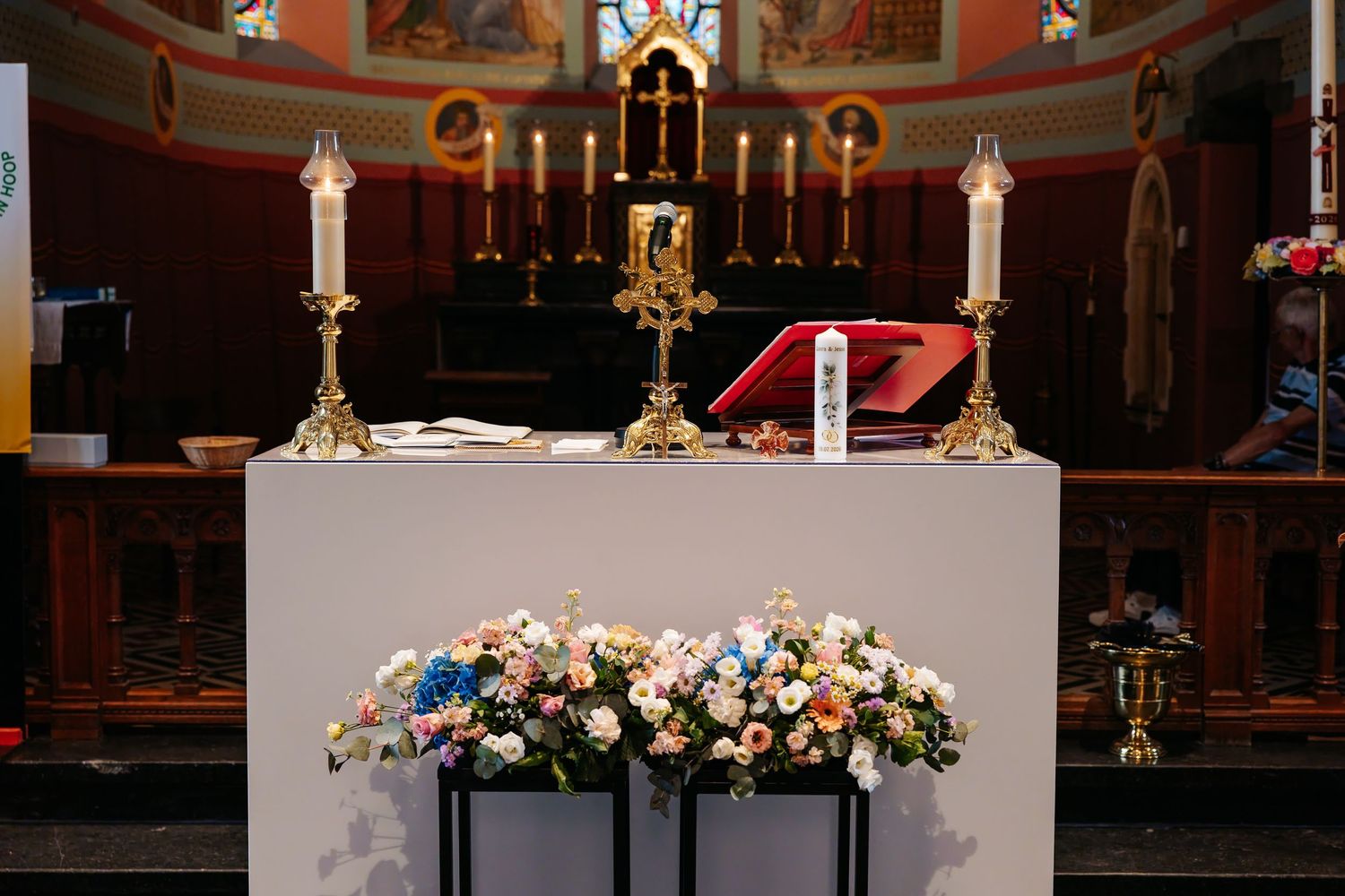 Elegant church altar decorated with colorful flowers and golden candlesticks.