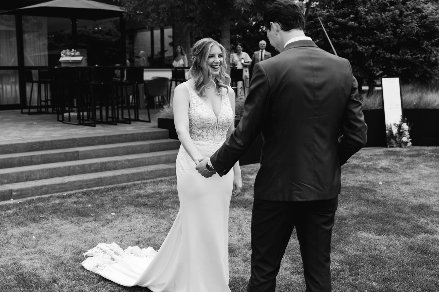 Black and white photo of bride and groom sharing a joyful first look moment outdoors.