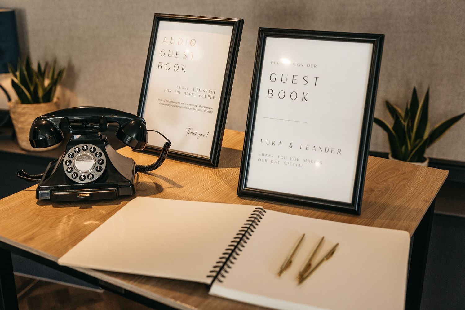 Wedding guest book table with vintage black rotary phone, framed signs, and spiral notebook.